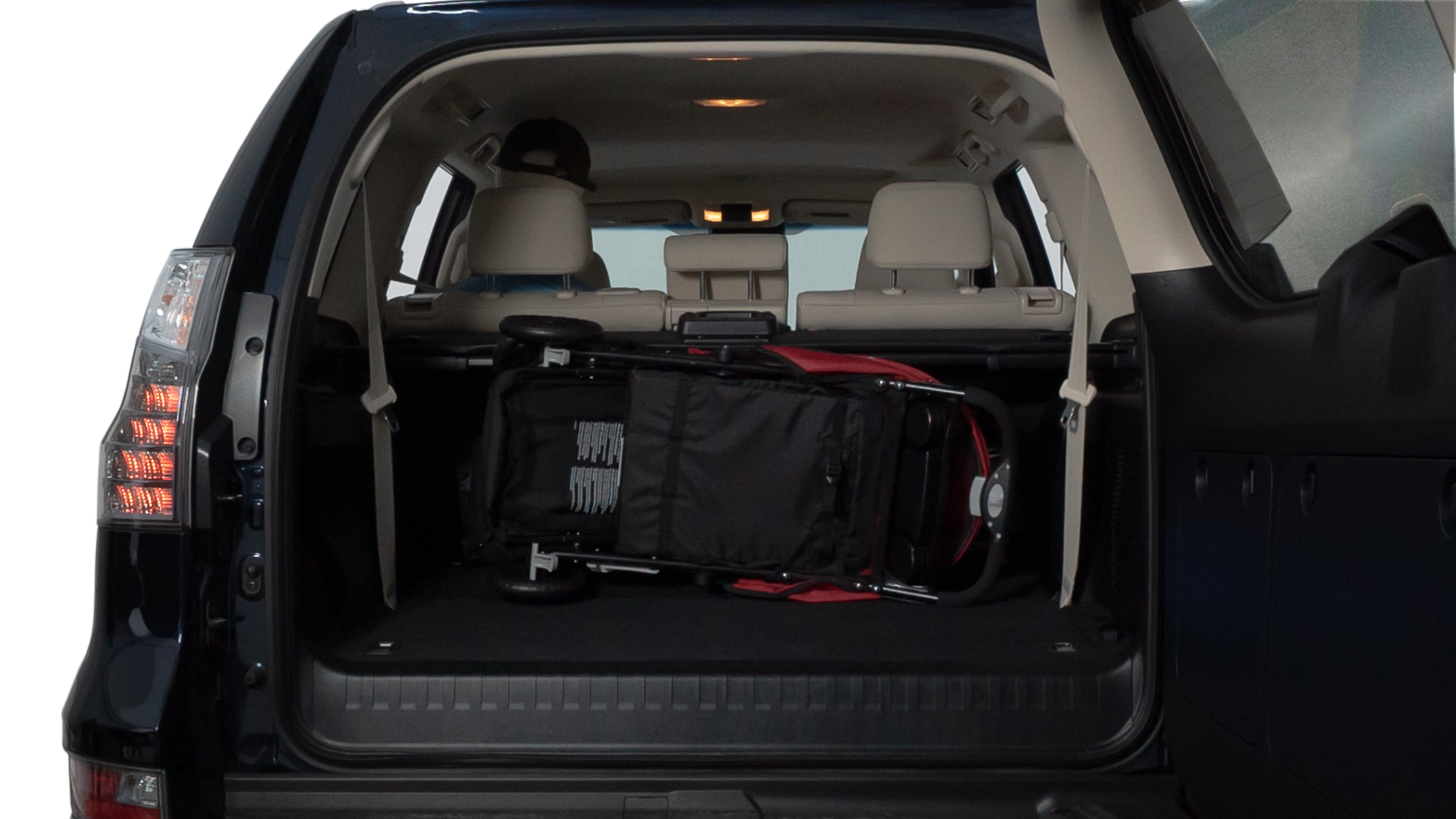 The trunk lid is open showing full view of the trunk. A baby stroller, three grocery carriers, two camping chairs in the carrying bag, and a set of golf clubs are placed inside.