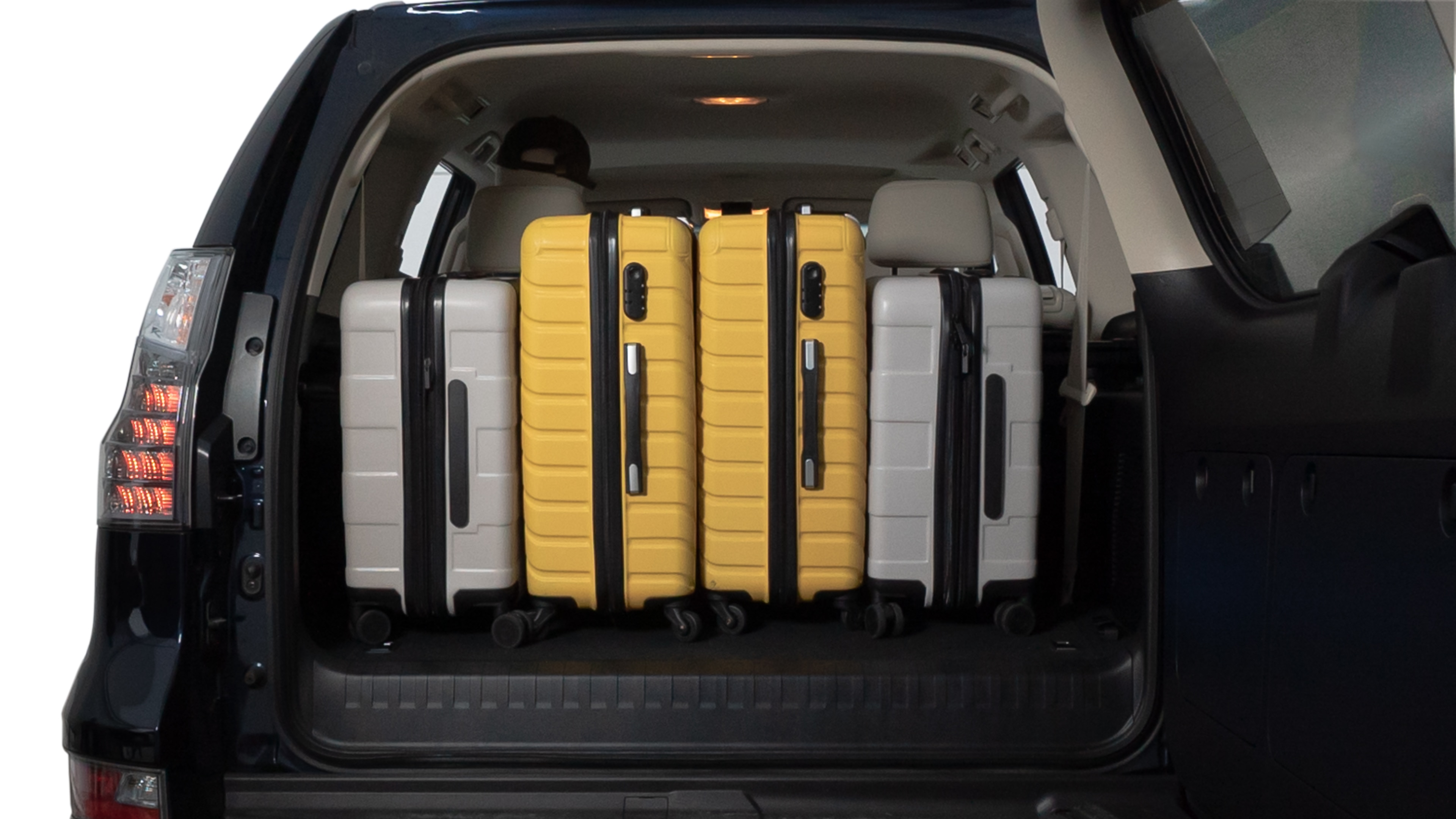 The trunk lid is open, showing full view of the trunk space. Two medium and two small suitcases are placed inside.