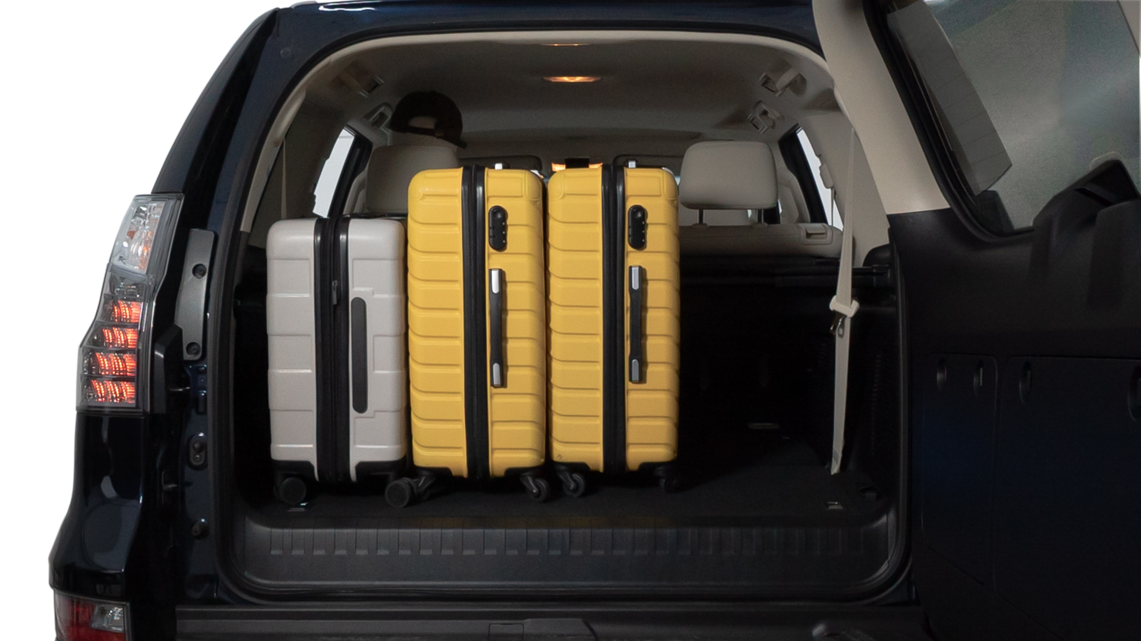 The trunk lid is open, showing full view of the trunk space. Two medium and two small suitcases are placed inside.