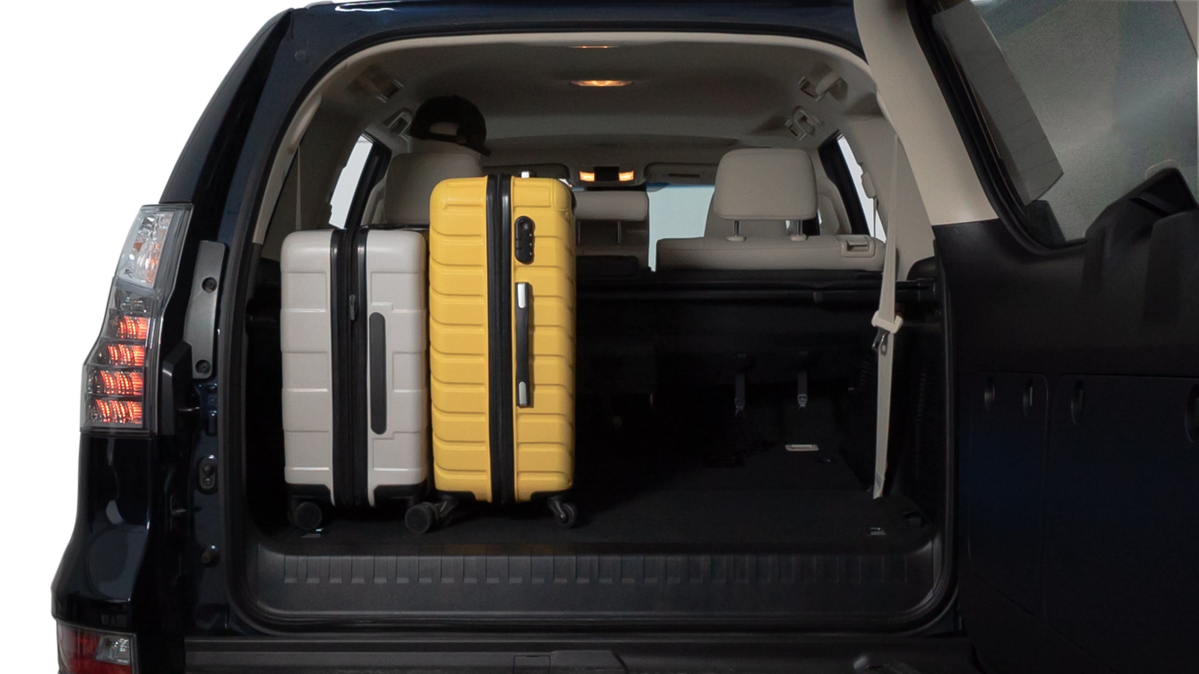 The trunk lid is open, showing full view of the trunk space. Two medium and two small suitcases are placed inside.
