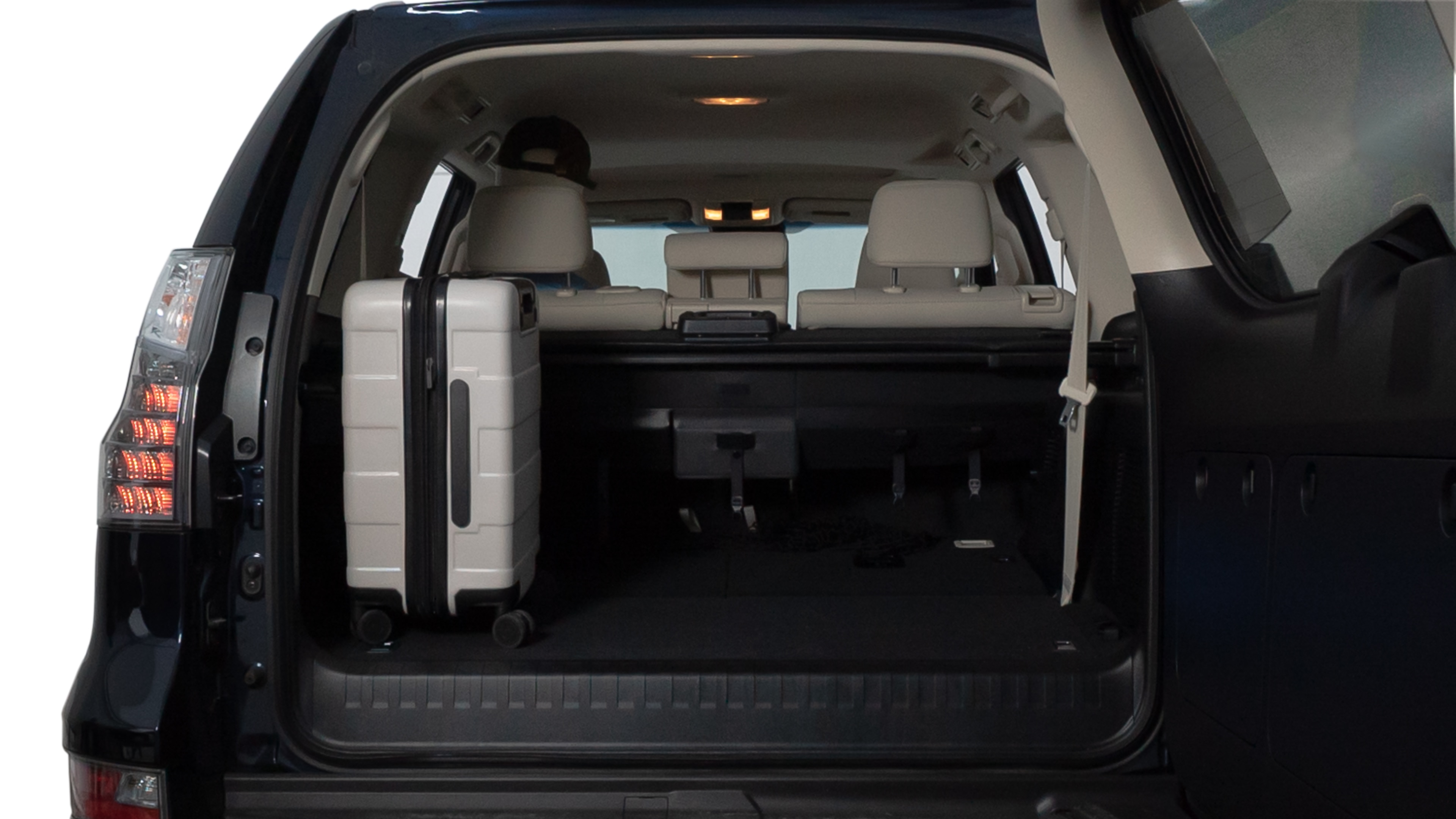 The trunk lid is open, showing full view of the trunk space. Two medium and two small suitcases are placed inside.