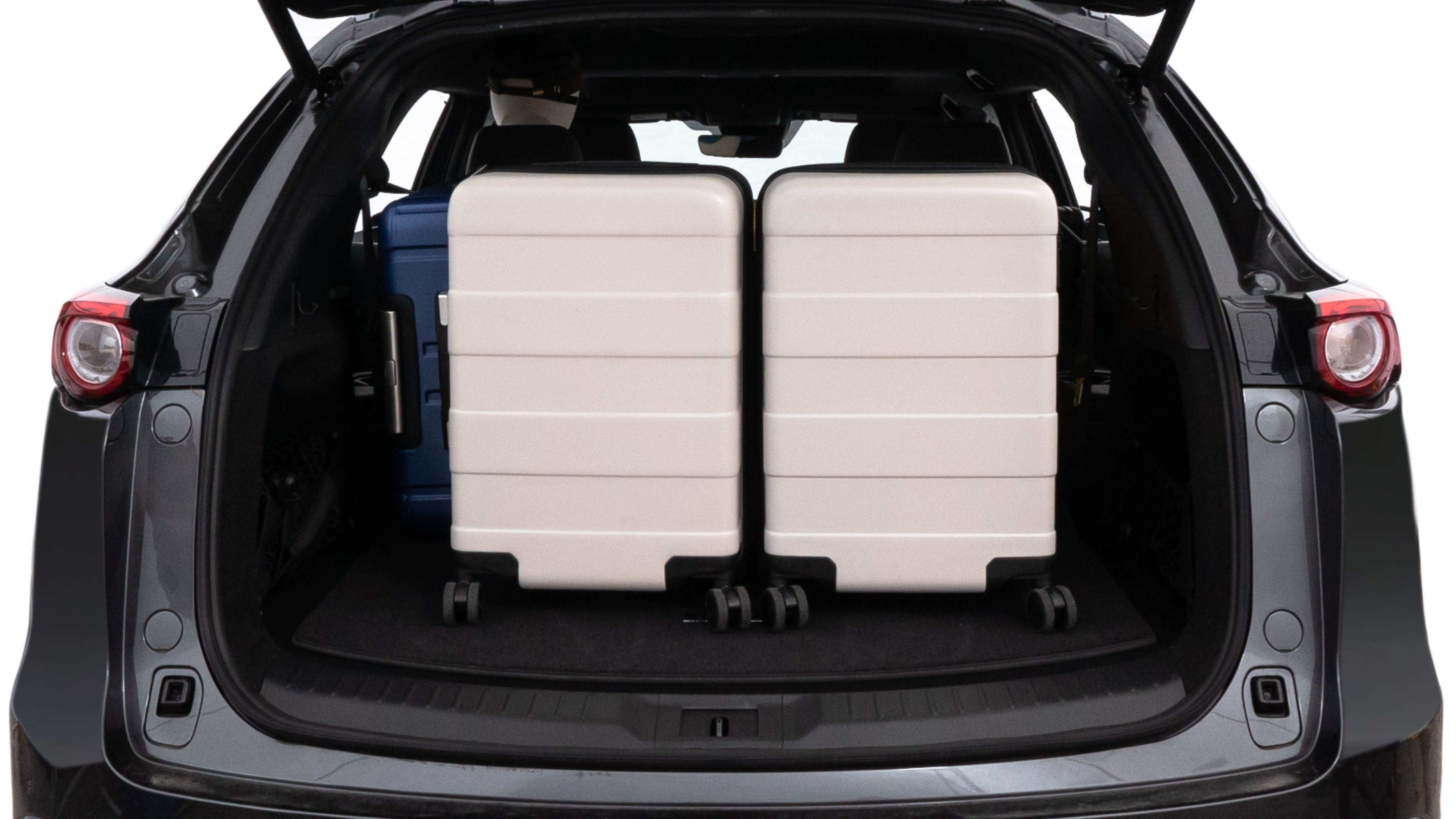 The trunk lid is open, showing full view of the trunk space. One large, two medium, and two small suitcases are placed inside.
