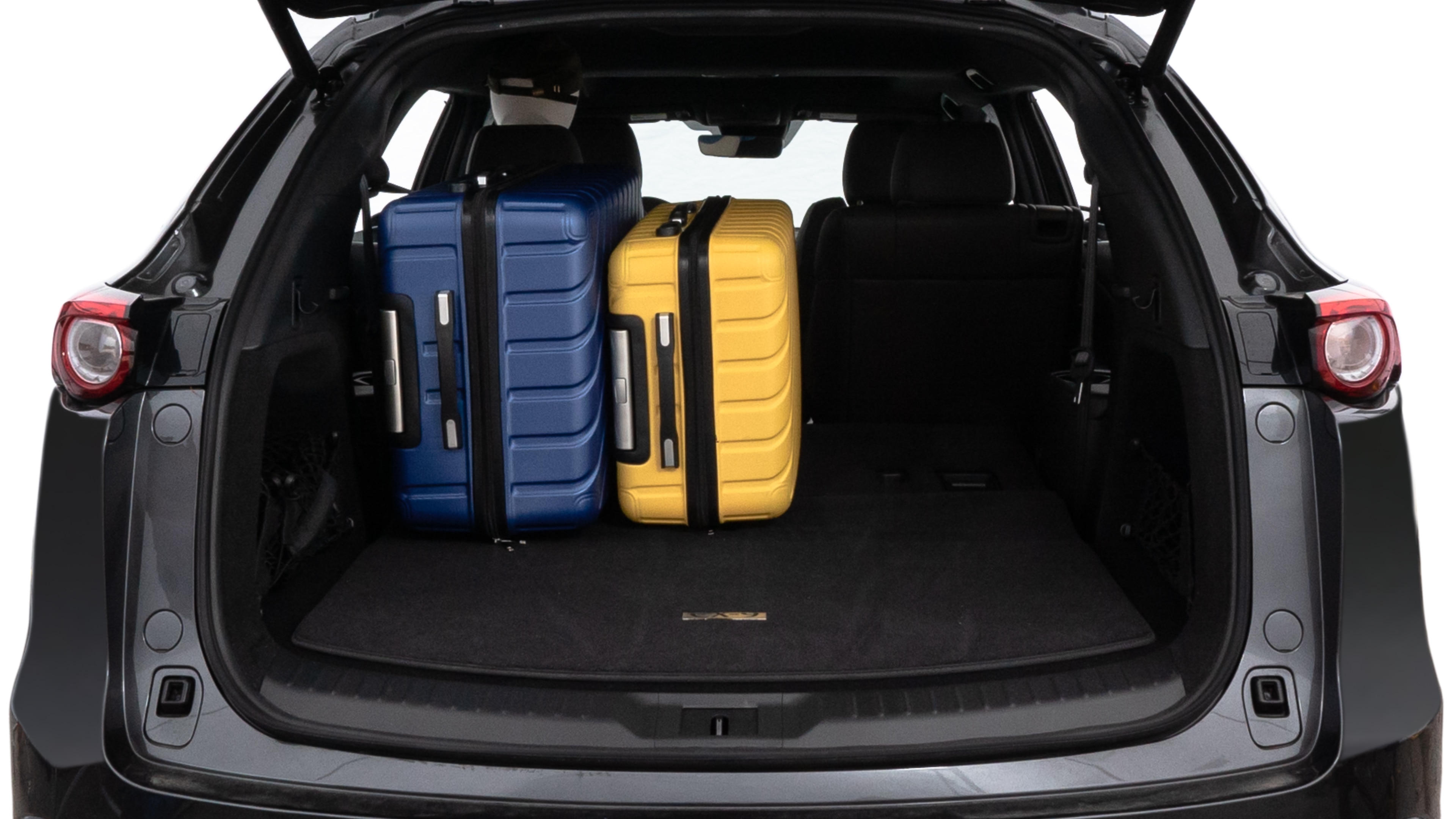 The trunk lid is open, showing full view of the trunk space. One large, two medium, and two small suitcases are placed inside.