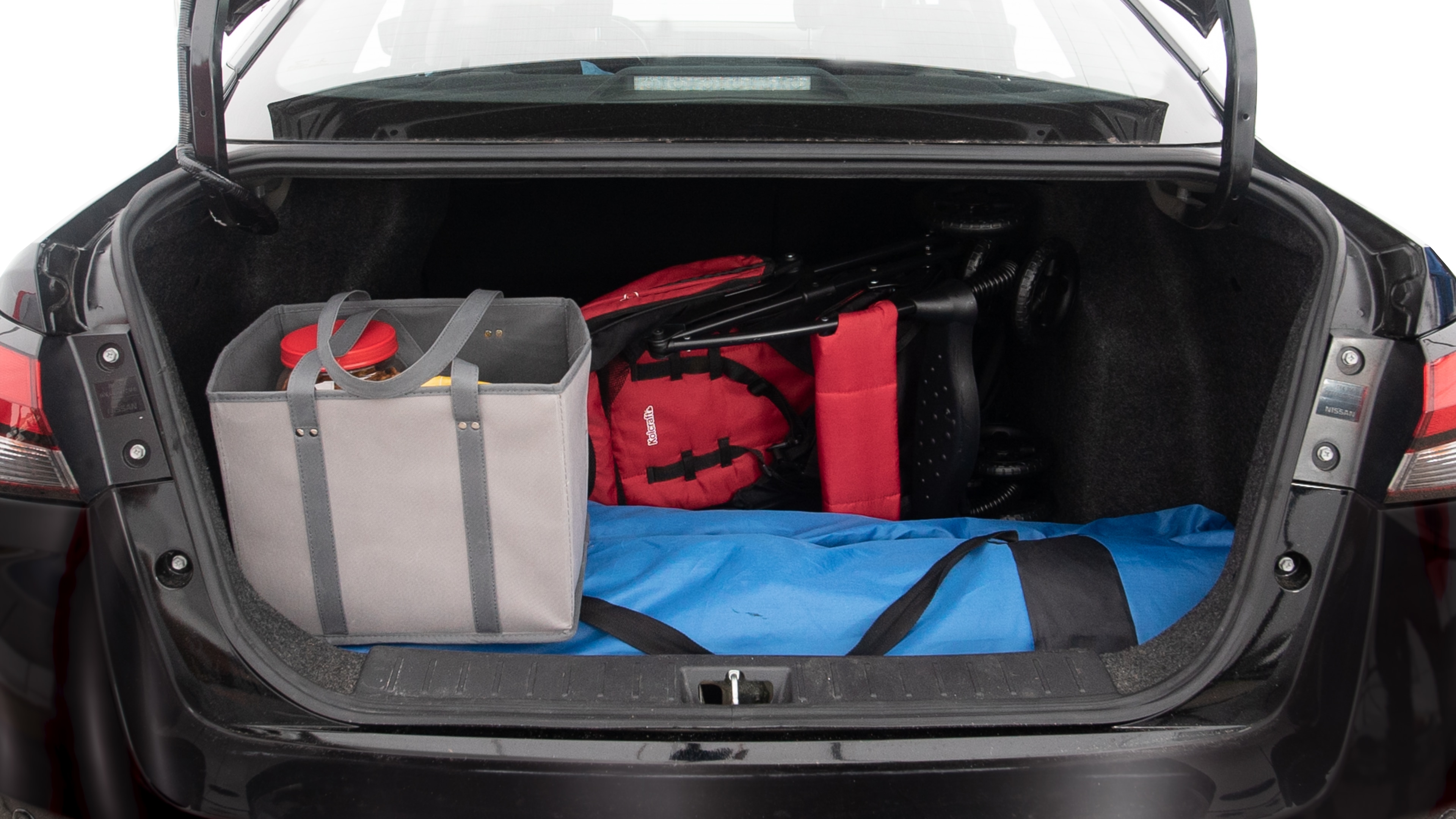 The trunk lid is open showing full view of the trunk. A baby stroller, three grocery carriers, two camping chairs in the carrying bag, and a set of golf clubs are placed inside.