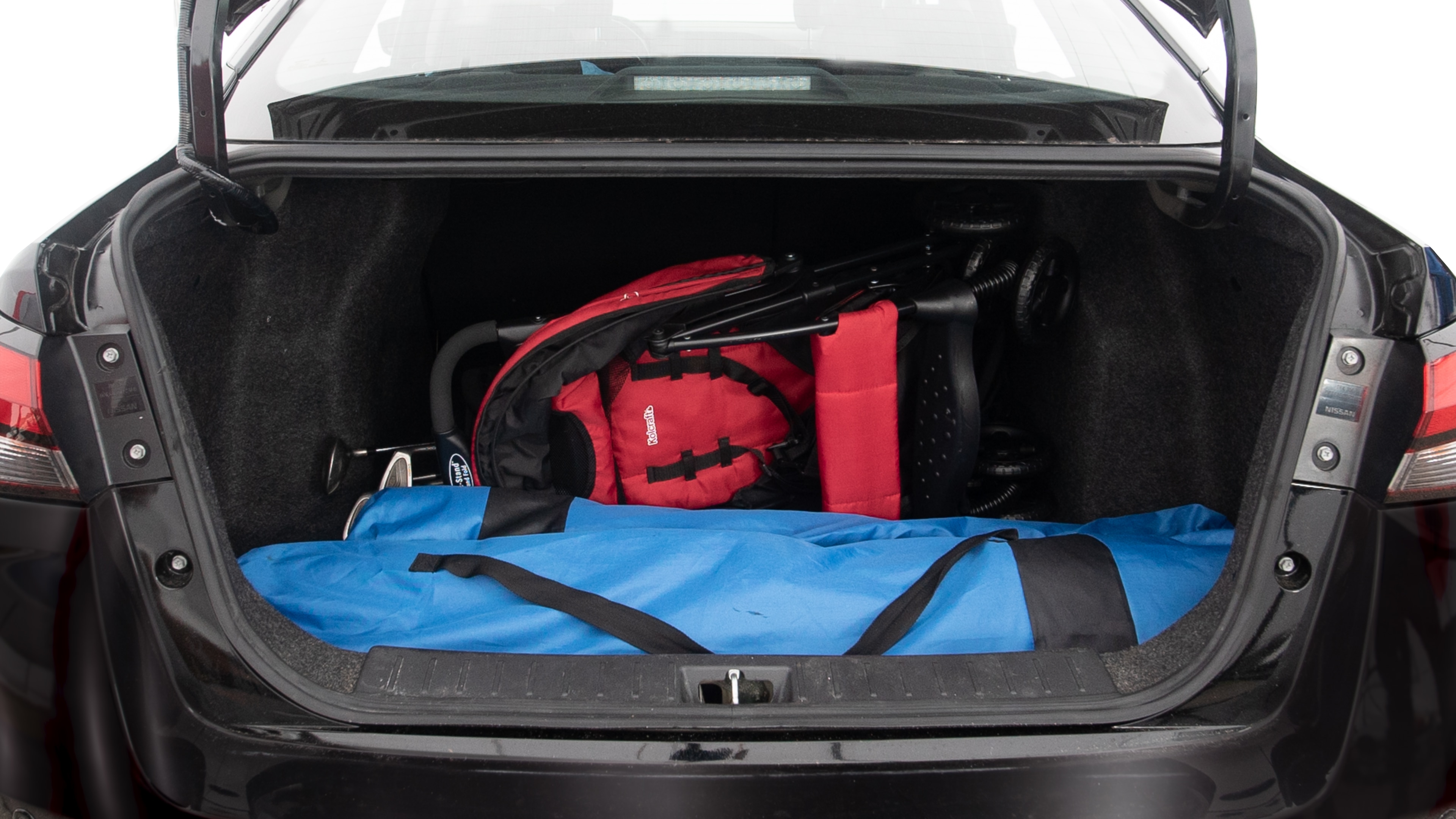 The trunk lid is open showing full view of the trunk. A baby stroller, three grocery carriers, two camping chairs in the carrying bag, and a set of golf clubs are placed inside.