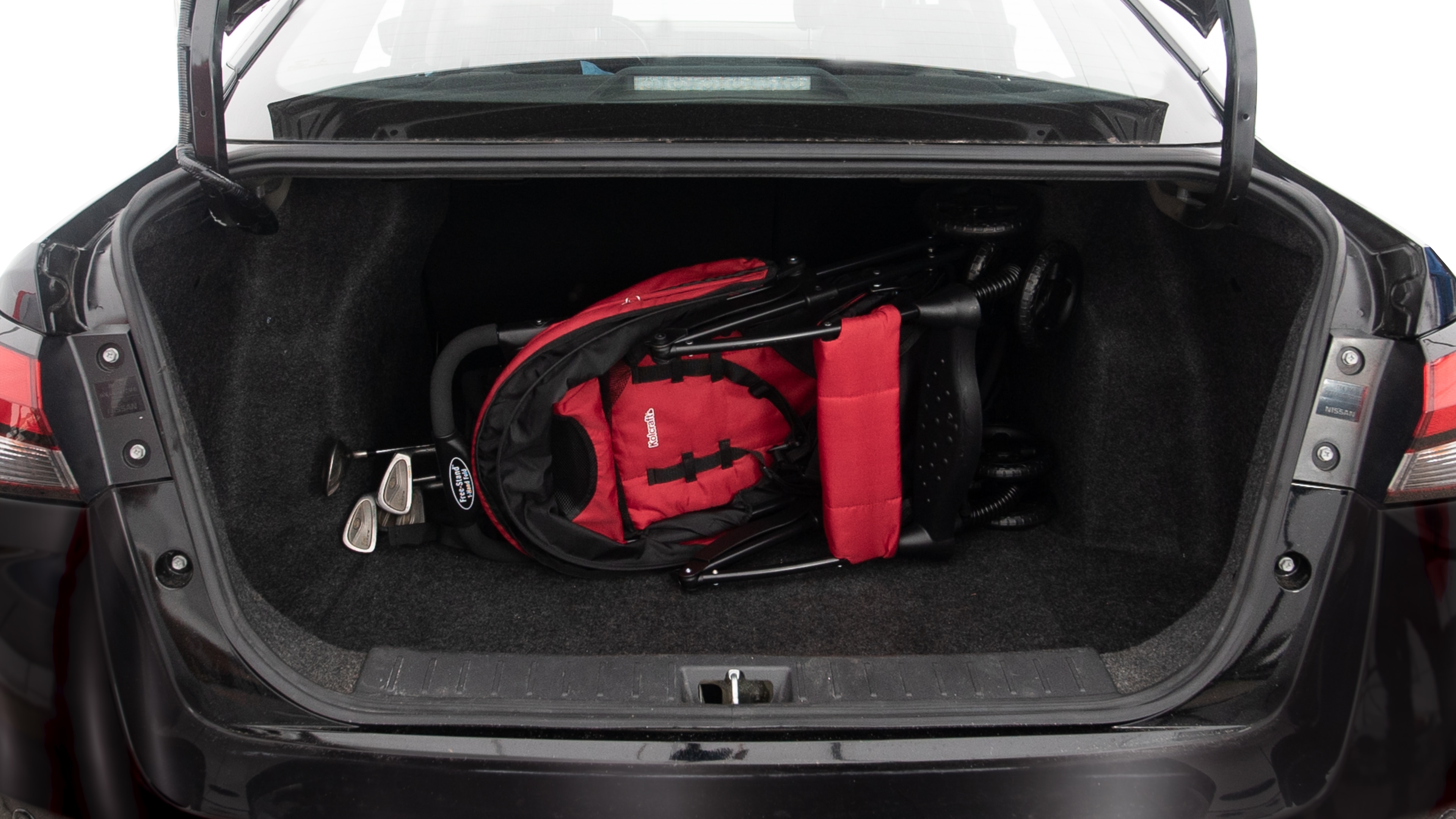 The trunk lid is open showing full view of the trunk. A baby stroller, three grocery carriers, two camping chairs in the carrying bag, and a set of golf clubs are placed inside.