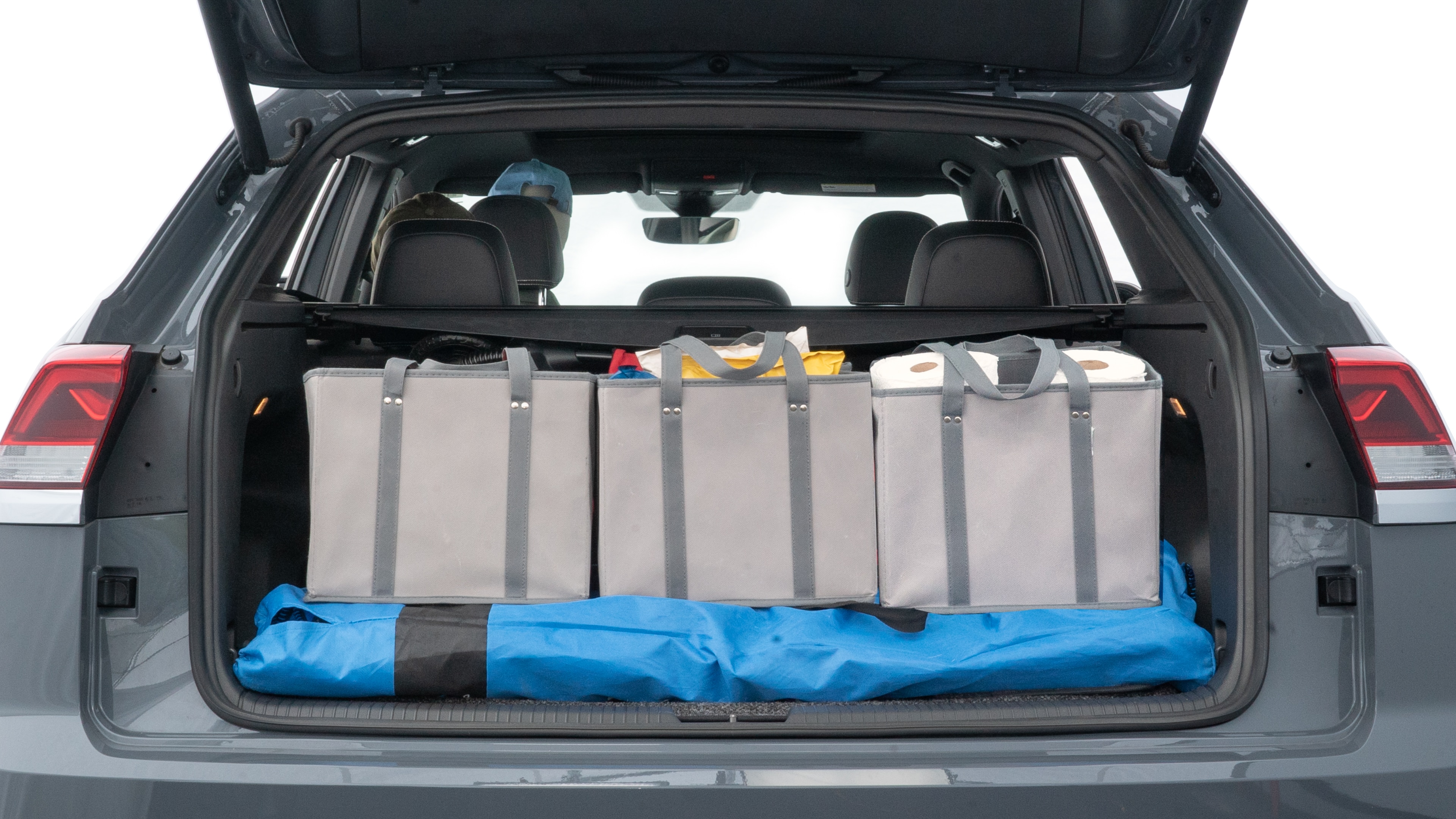 The trunk lid is open showing full view of the trunk. A baby stroller, three grocery carriers, two camping chairs in the carrying bag, and a set of golf clubs are placed inside.