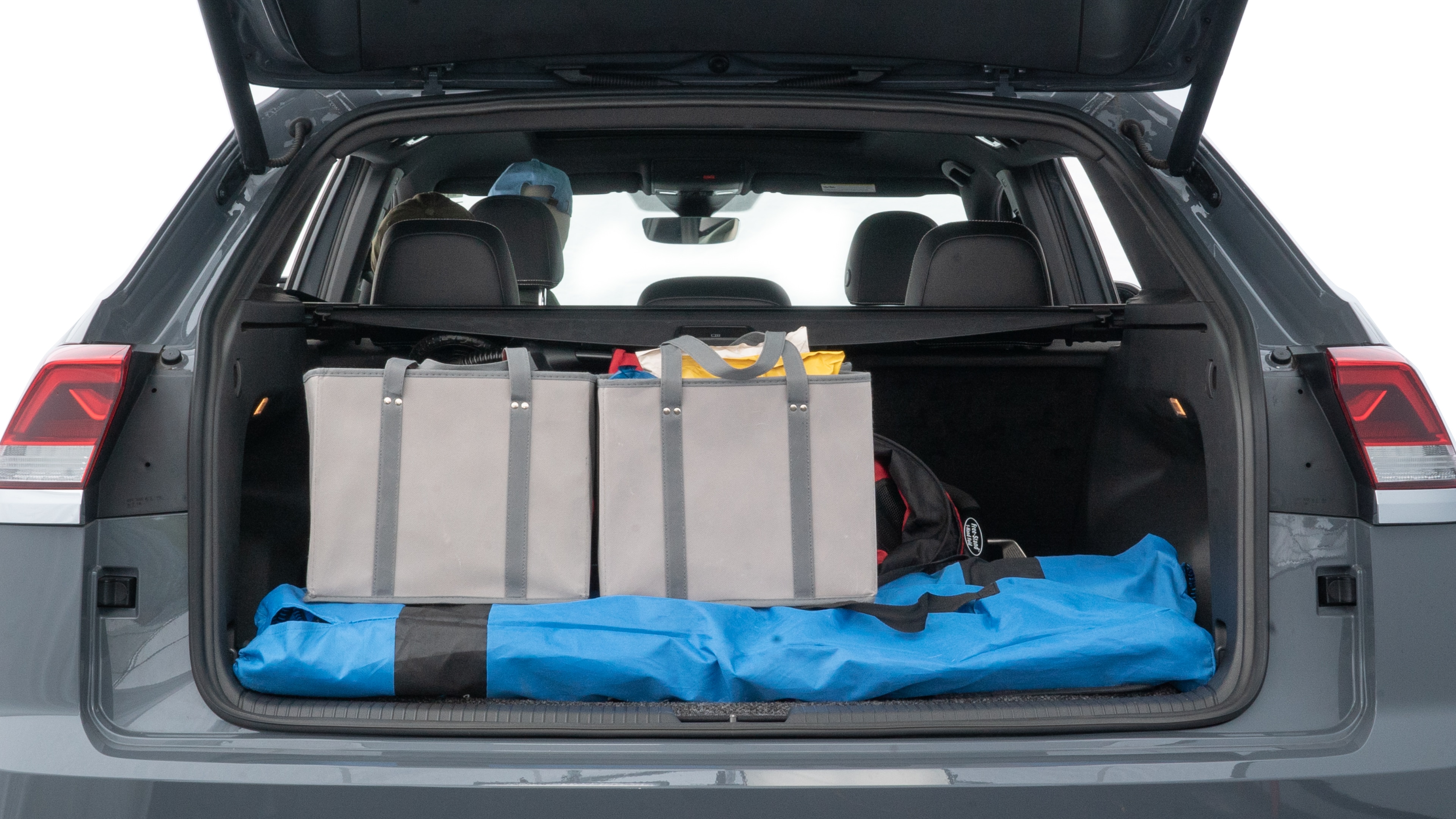 The trunk lid is open showing full view of the trunk. A baby stroller, three grocery carriers, two camping chairs in the carrying bag, and a set of golf clubs are placed inside.