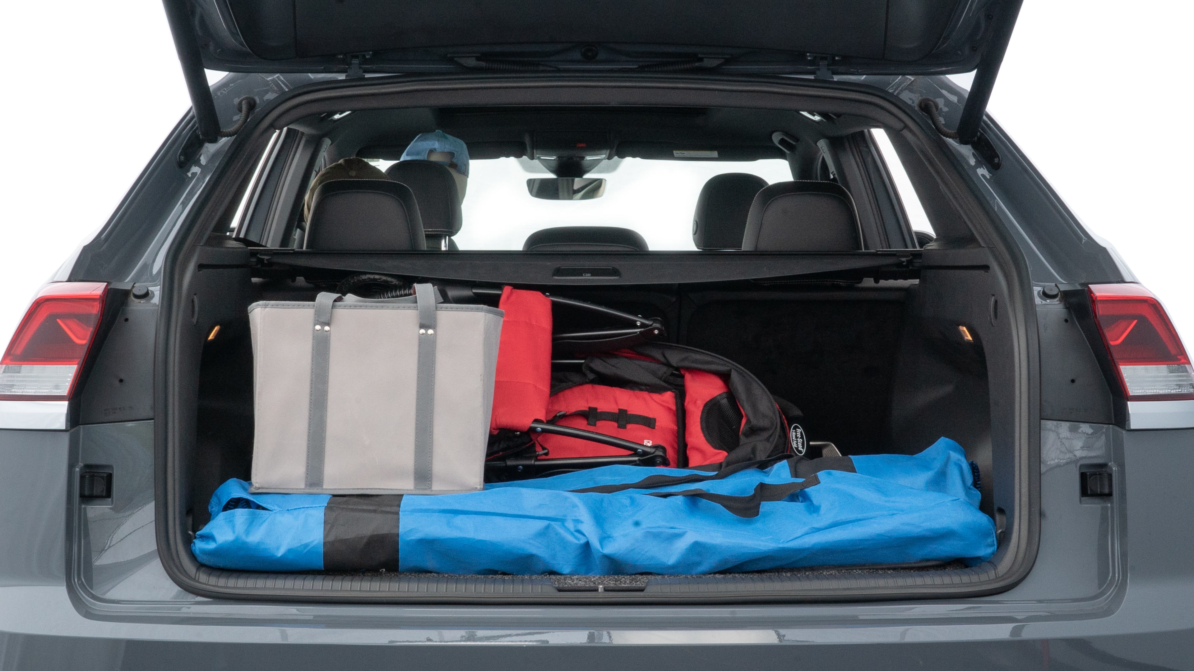 The trunk lid is open showing full view of the trunk. A baby stroller, three grocery carriers, two camping chairs in the carrying bag, and a set of golf clubs are placed inside.