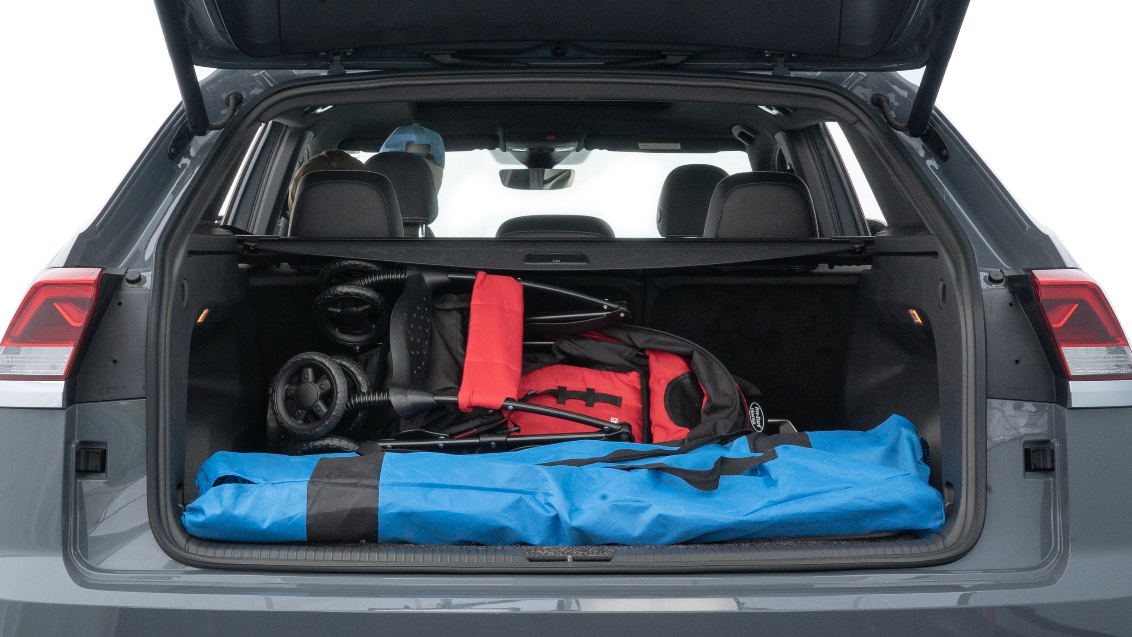 The trunk lid is open showing full view of the trunk. A baby stroller, three grocery carriers, two camping chairs in the carrying bag, and a set of golf clubs are placed inside.
