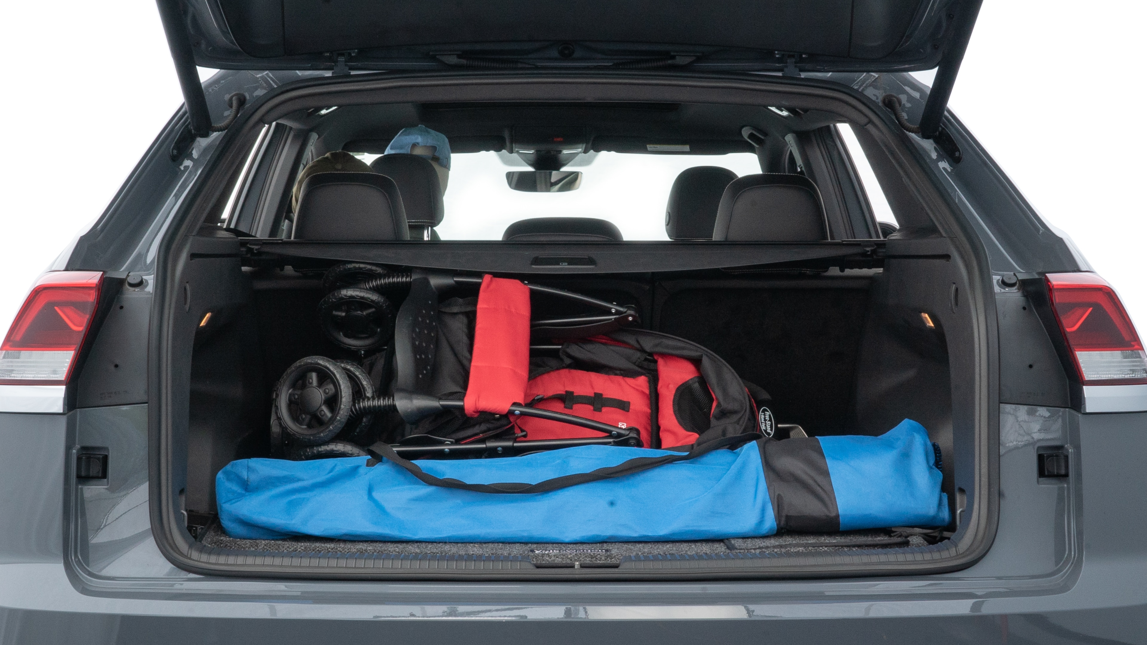 The trunk lid is open showing full view of the trunk. A baby stroller, three grocery carriers, two camping chairs in the carrying bag, and a set of golf clubs are placed inside.