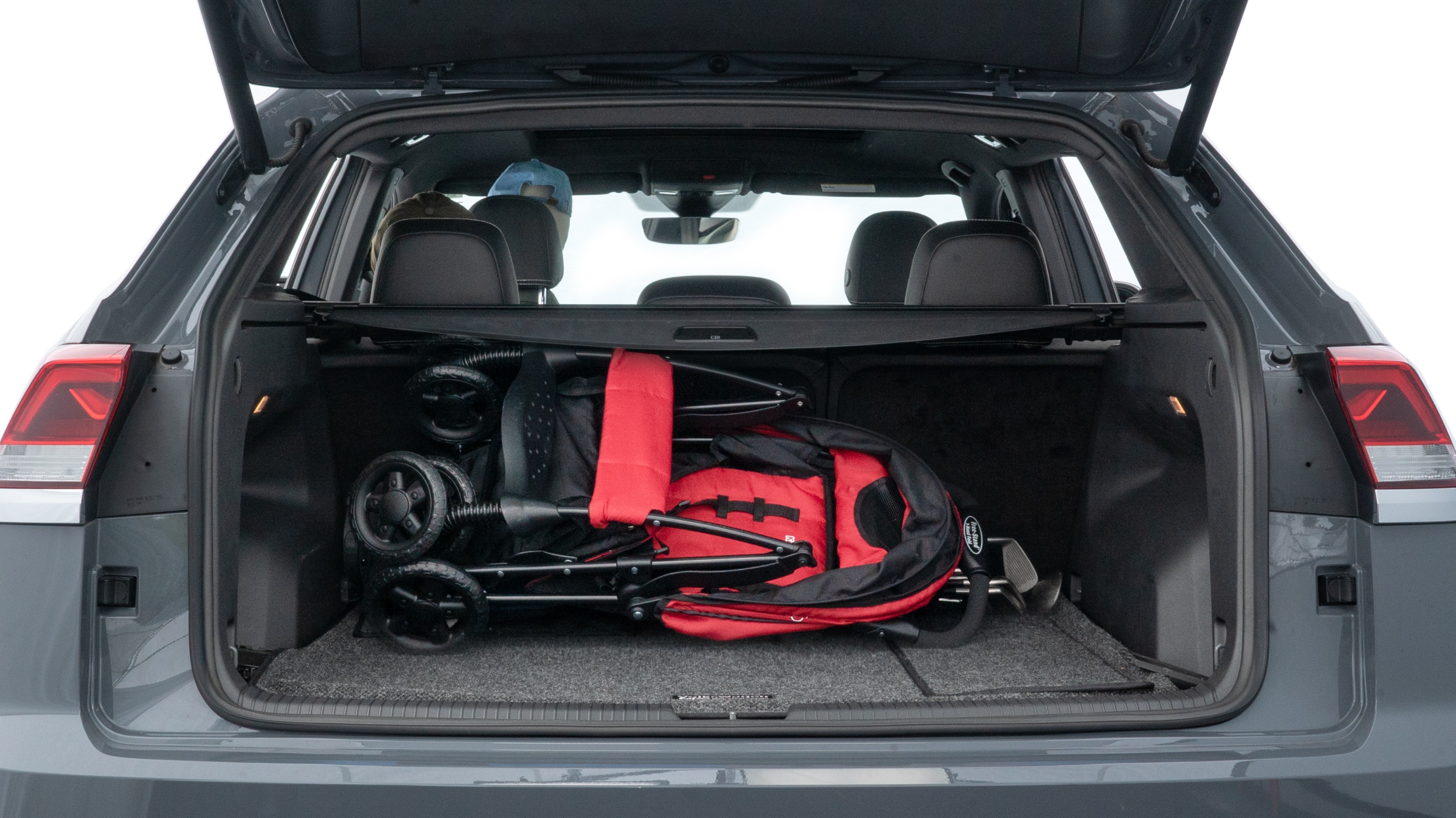 The trunk lid is open showing full view of the trunk. A baby stroller, three grocery carriers, two camping chairs in the carrying bag, and a set of golf clubs are placed inside.