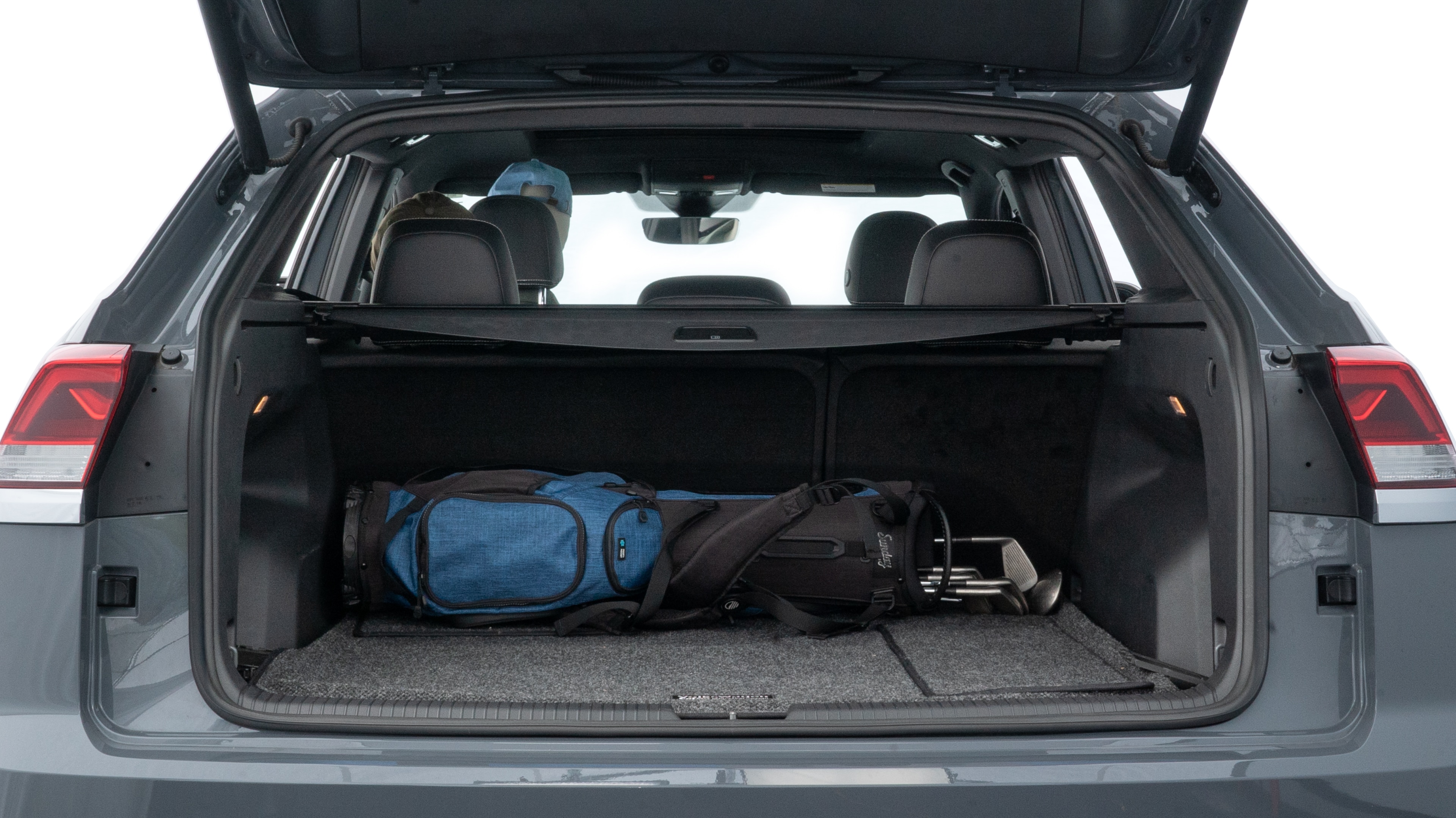 The trunk lid is open showing full view of the trunk. A baby stroller, three grocery carriers, two camping chairs in the carrying bag, and a set of golf clubs are placed inside.