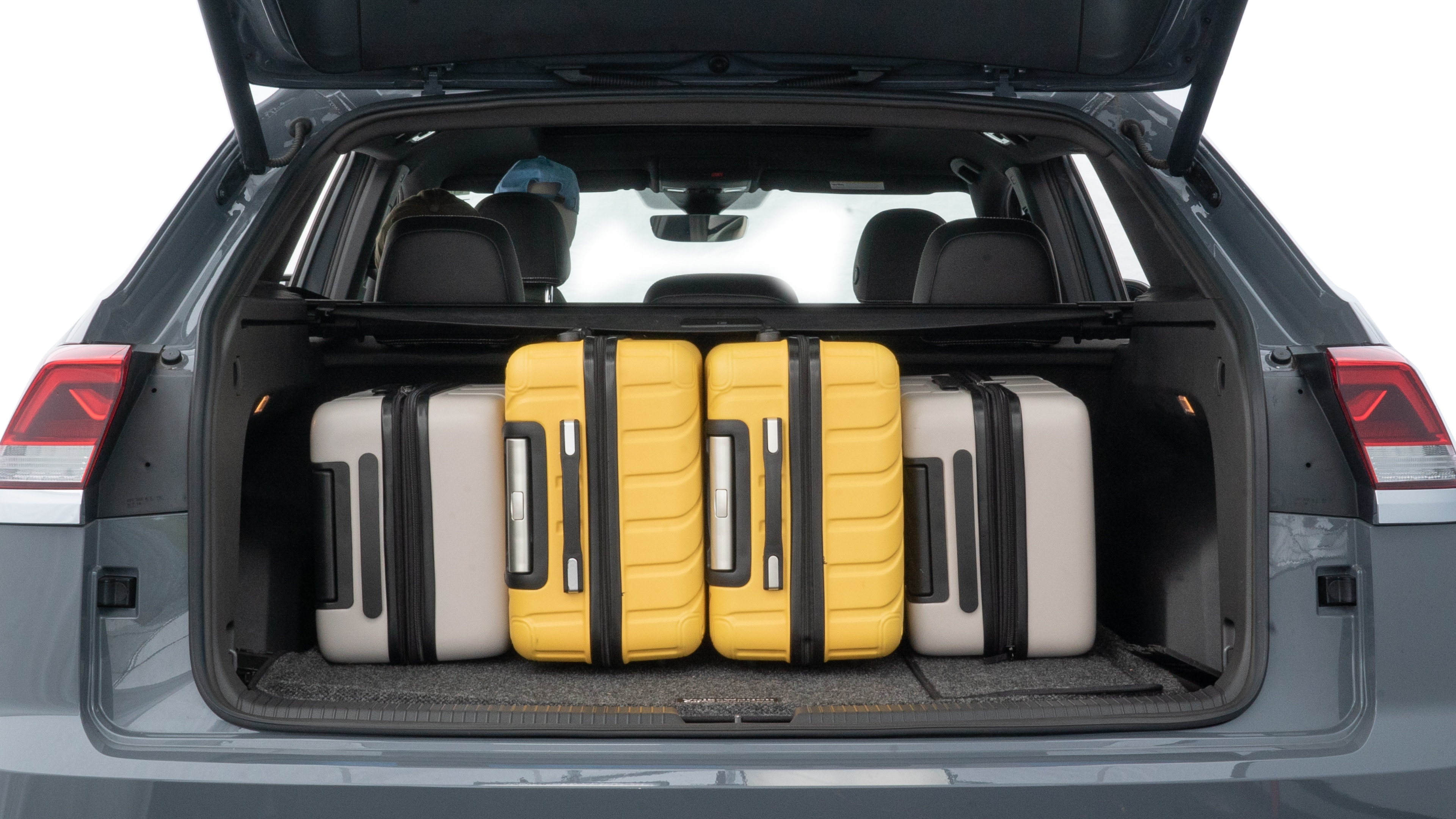 The trunk lid is open, showing full view of the trunk space. Two medium and two small suitcases are placed inside.