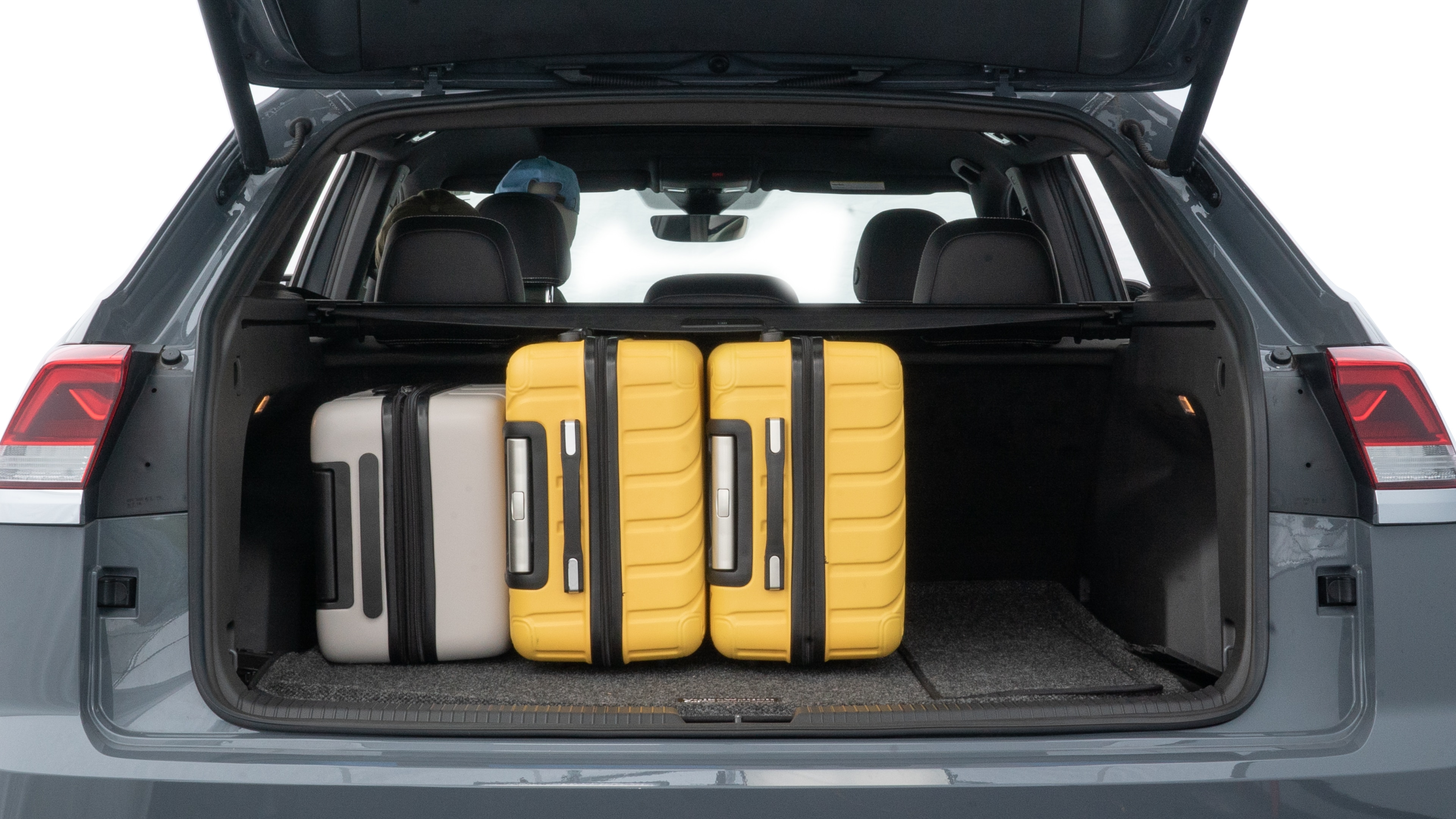 The trunk lid is open, showing full view of the trunk space. Two medium and two small suitcases are placed inside.