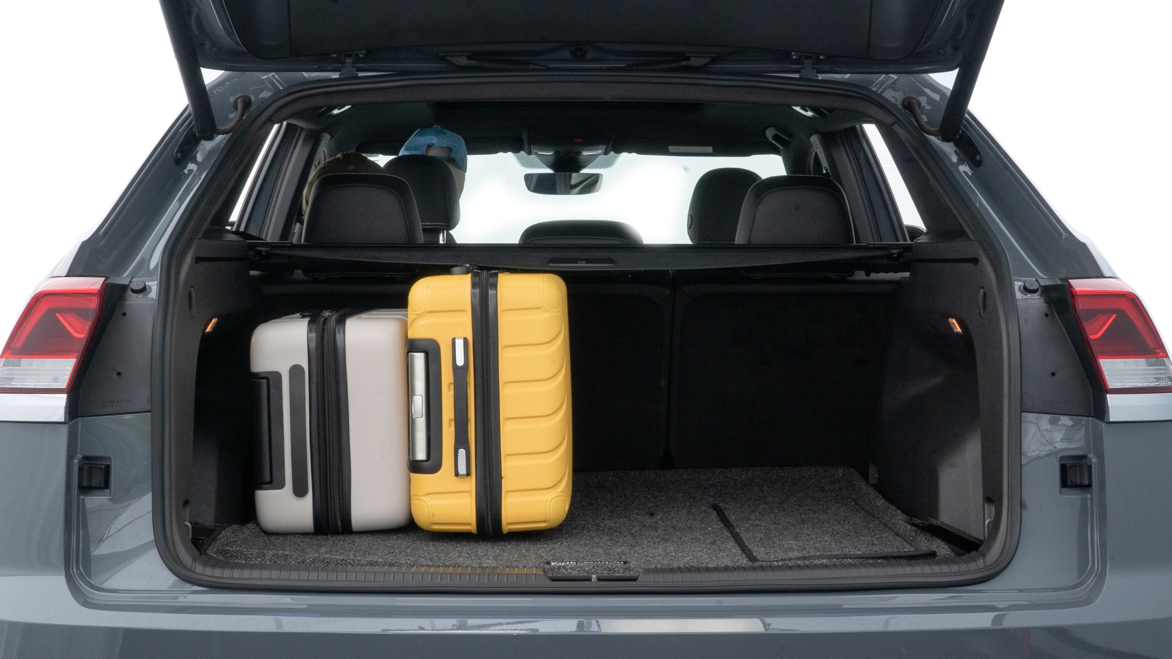 The trunk lid is open, showing full view of the trunk space. Two medium and two small suitcases are placed inside.