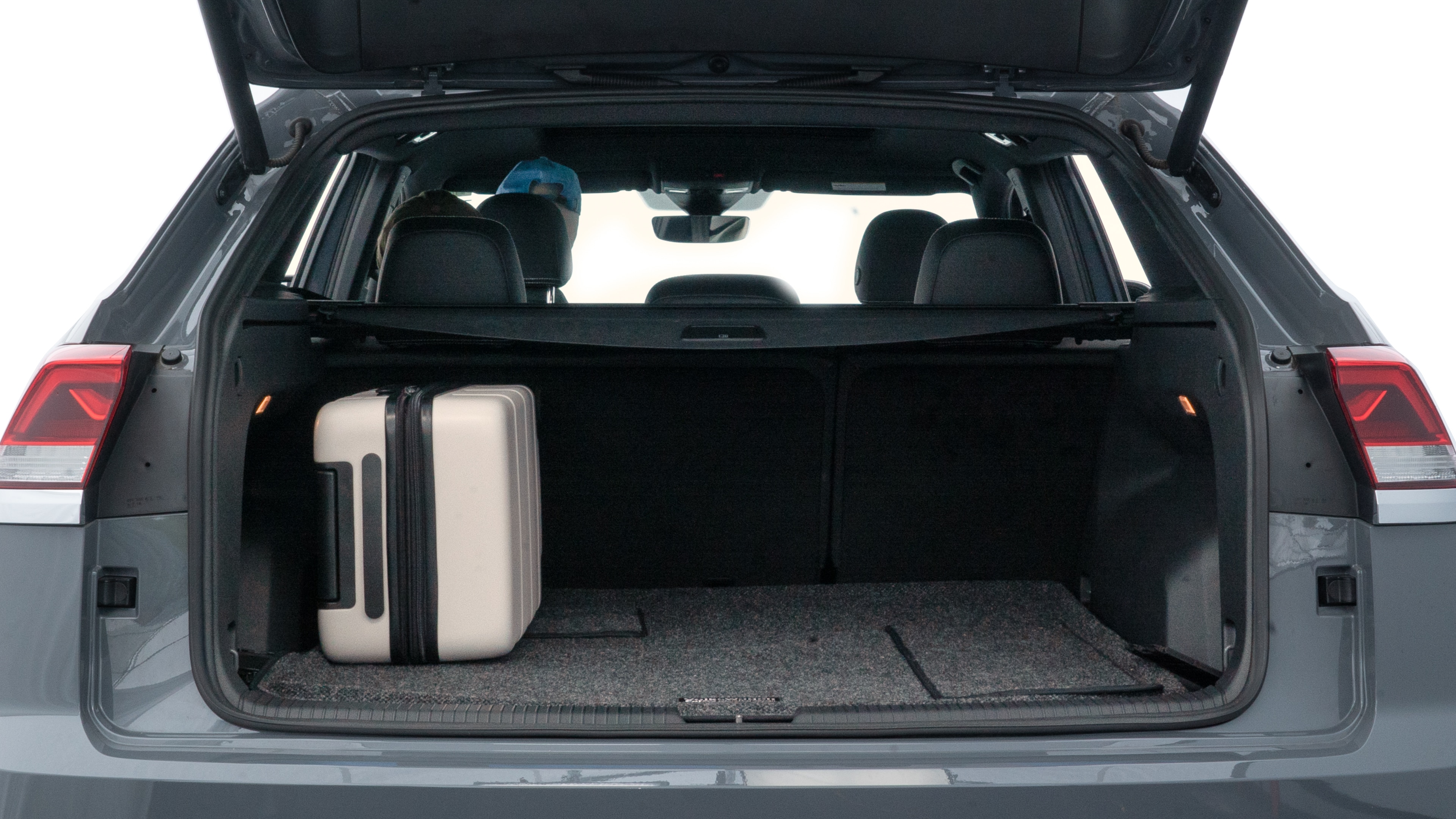 The trunk lid is open, showing full view of the trunk space. Two medium and two small suitcases are placed inside.