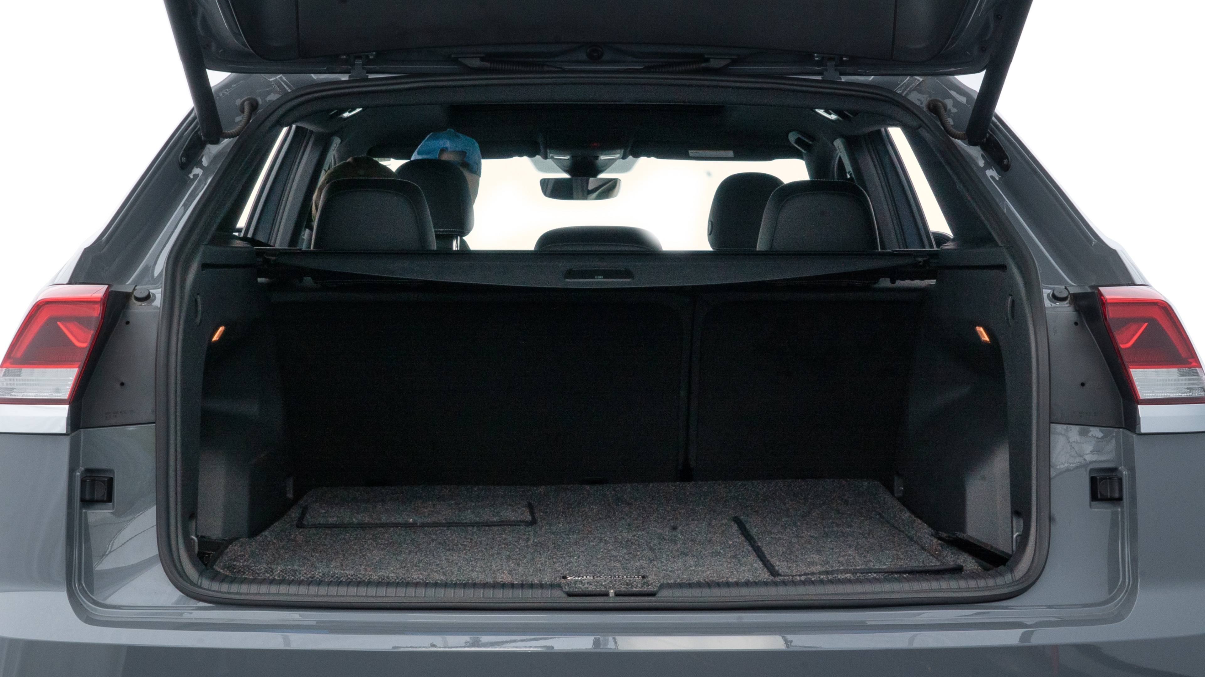 The trunk lid is open, showing full view of the trunk space. Two medium and two small suitcases are placed inside.