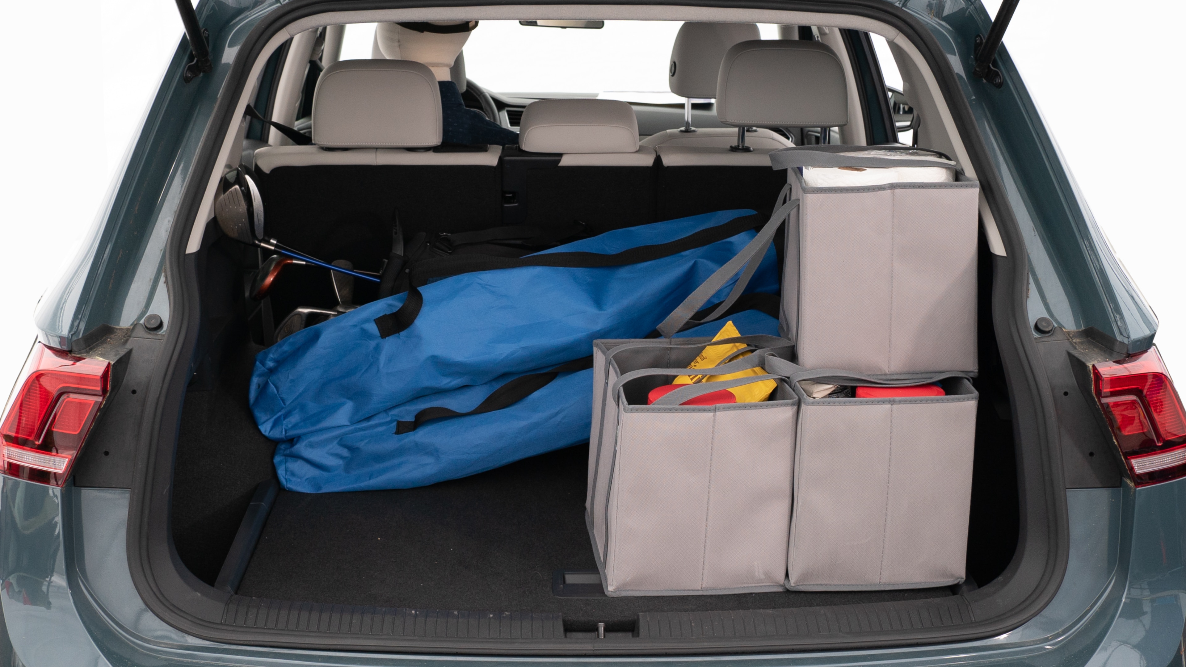 The trunk lid is open showing full view of the trunk. A baby stroller, three grocery carriers, two camping chairs in the carrying bag, and a set of golf clubs are placed inside.