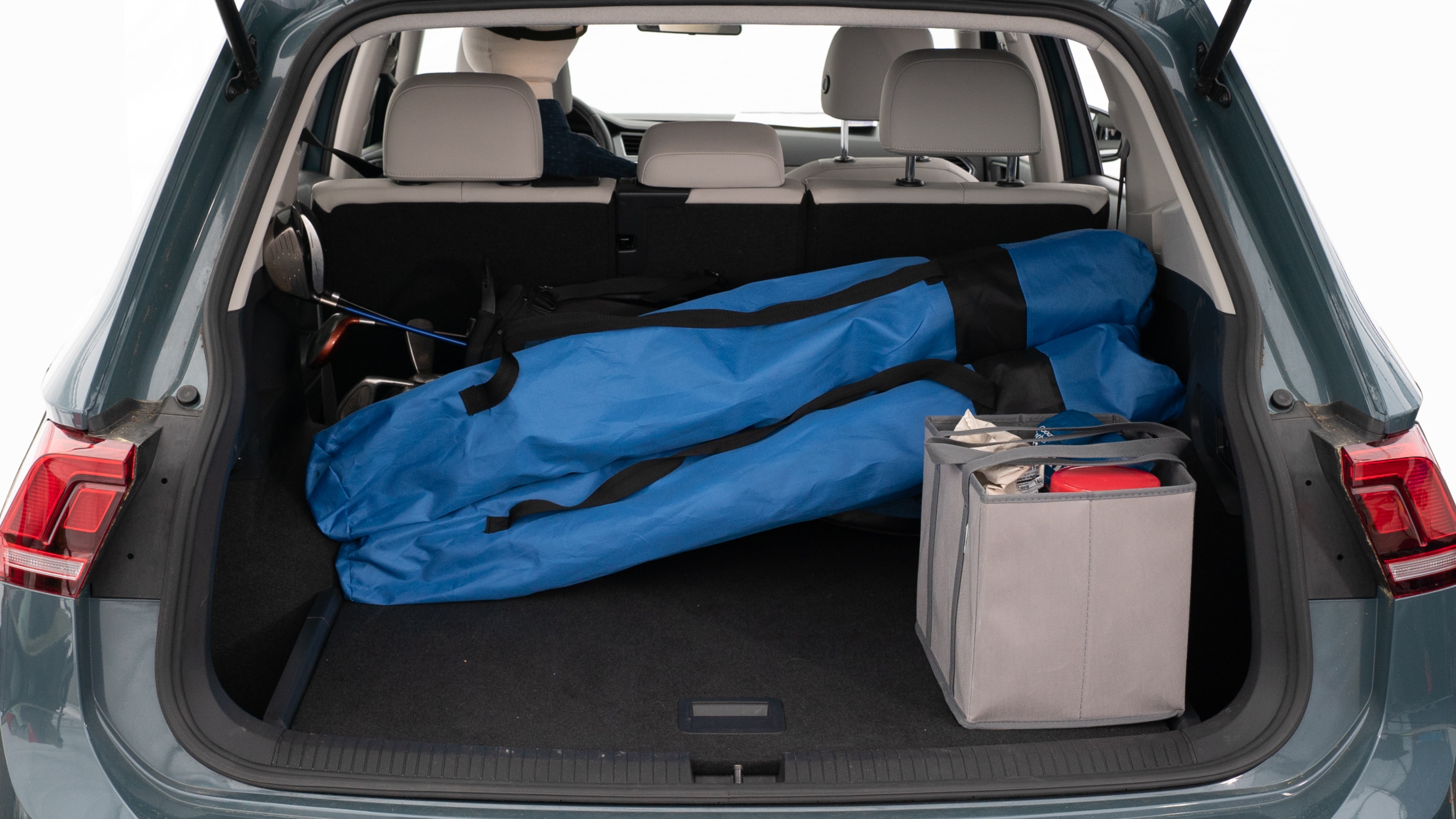 The trunk lid is open showing full view of the trunk. A baby stroller, three grocery carriers, two camping chairs in the carrying bag, and a set of golf clubs are placed inside.