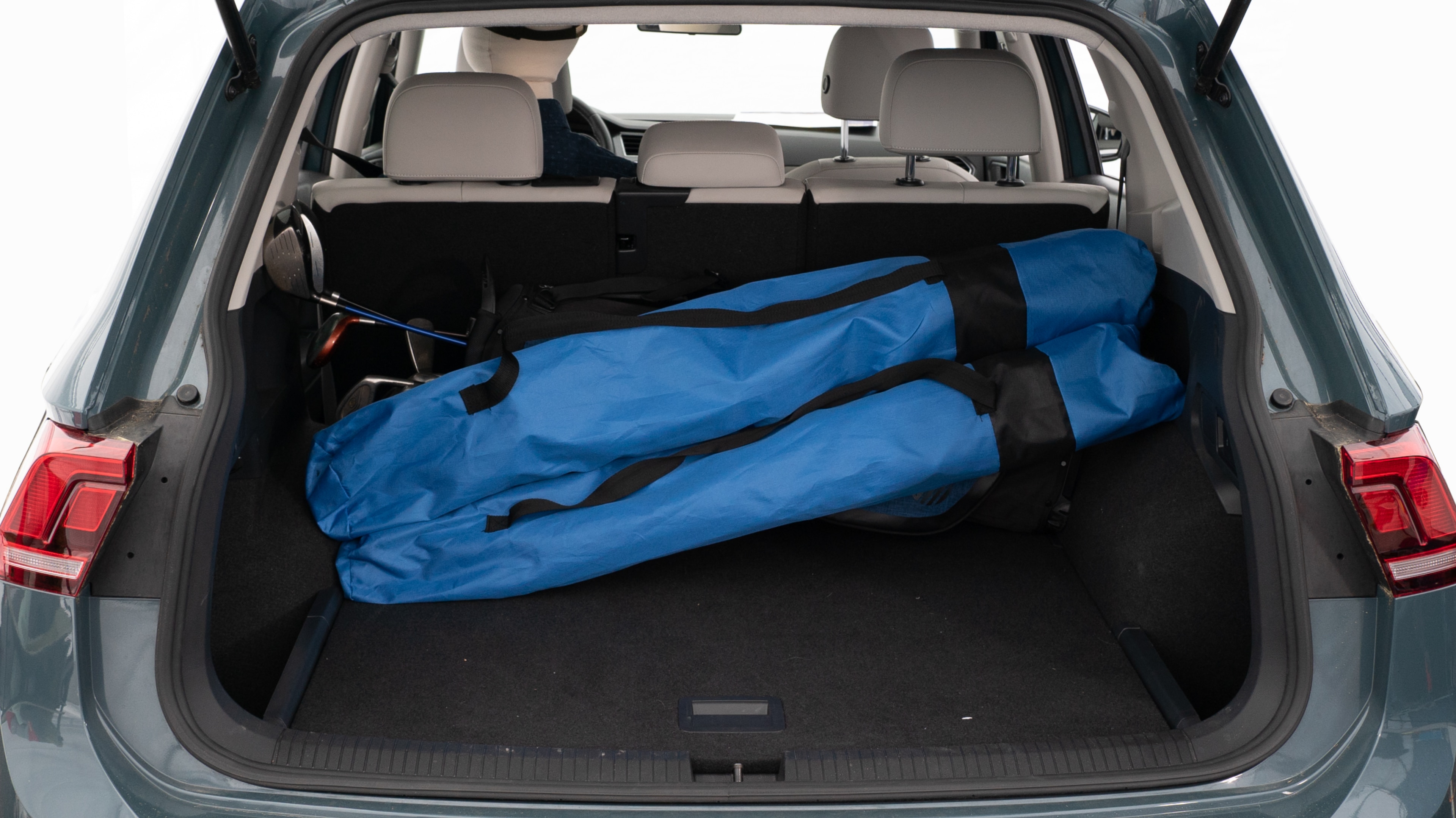 The trunk lid is open showing full view of the trunk. A baby stroller, three grocery carriers, two camping chairs in the carrying bag, and a set of golf clubs are placed inside.