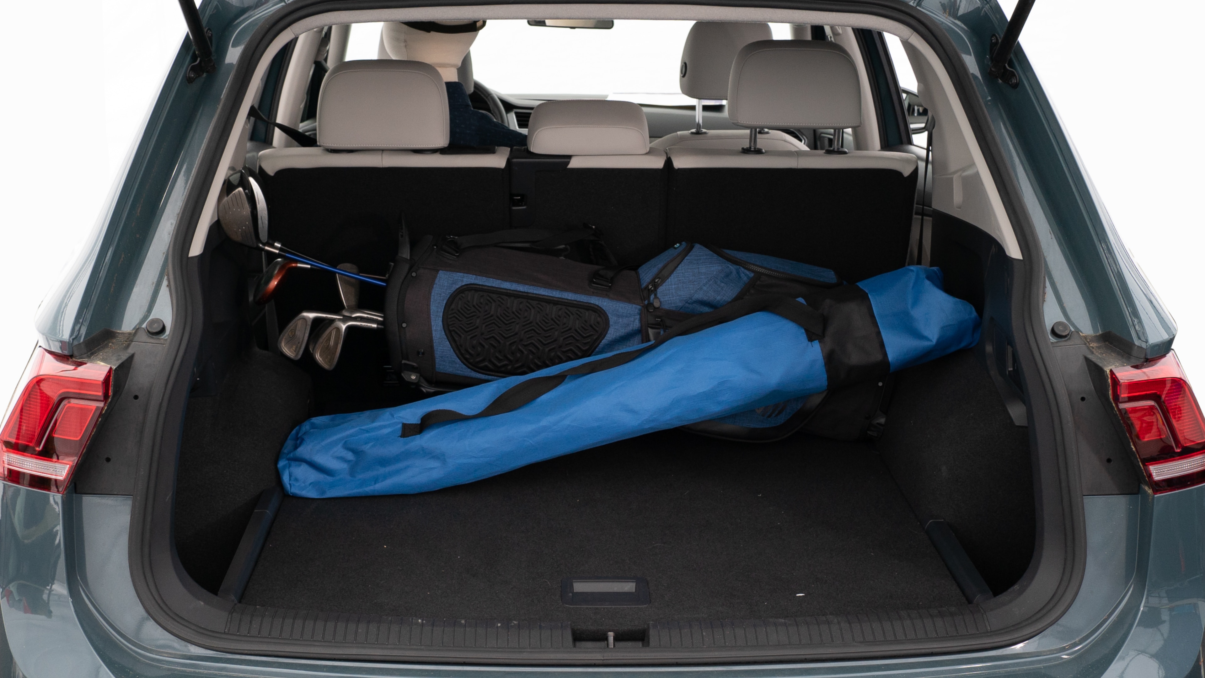 The trunk lid is open showing full view of the trunk. A baby stroller, three grocery carriers, two camping chairs in the carrying bag, and a set of golf clubs are placed inside.