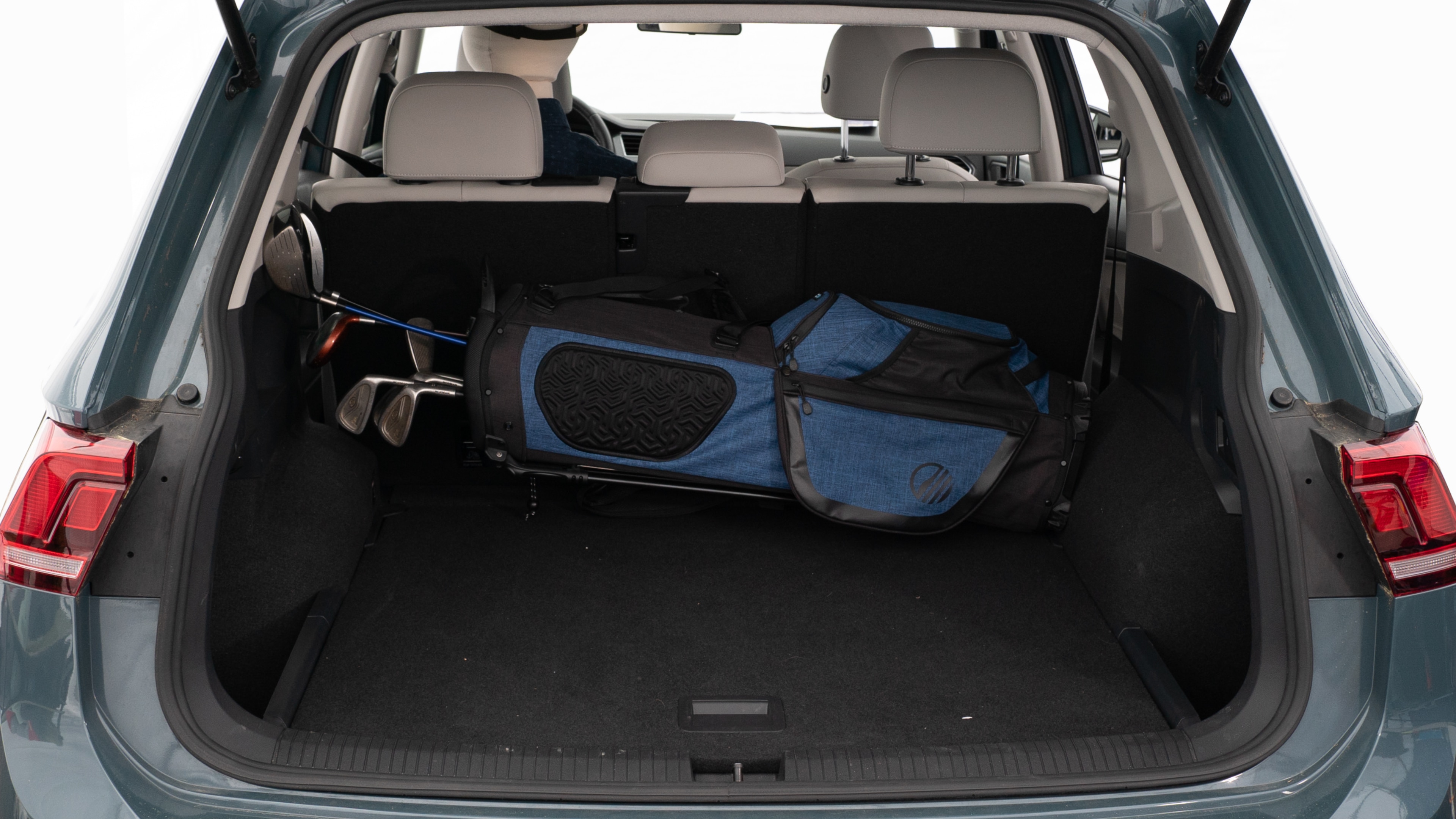 The trunk lid is open showing full view of the trunk. A baby stroller, three grocery carriers, two camping chairs in the carrying bag, and a set of golf clubs are placed inside.