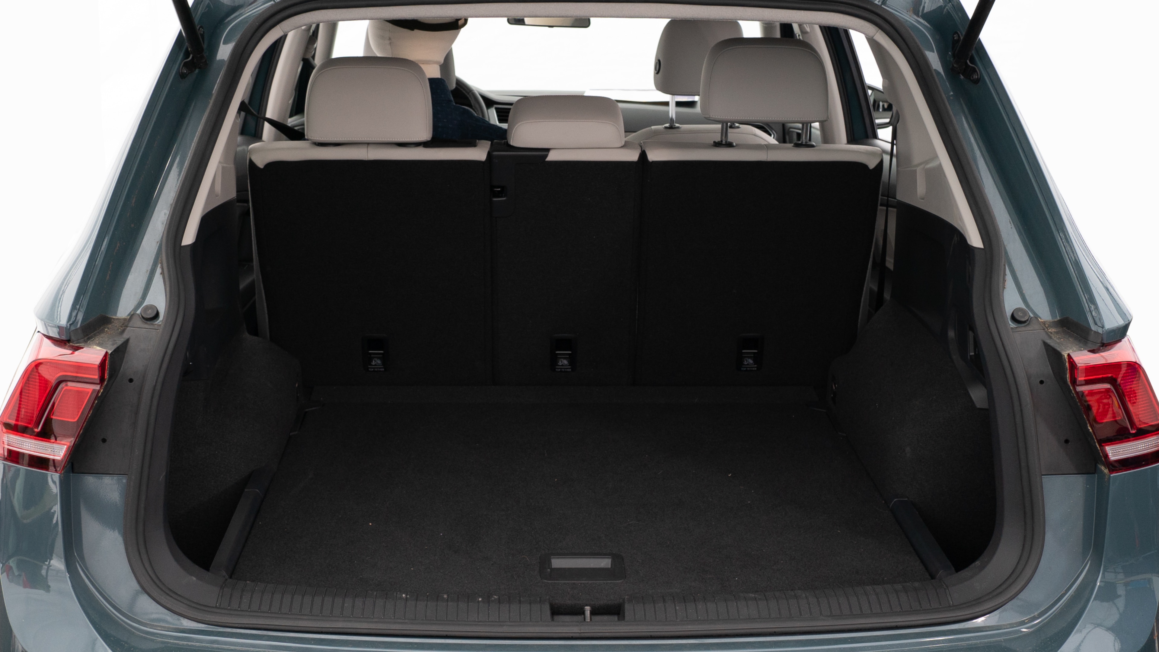 The trunk lid is open showing full view of the trunk. A baby stroller, three grocery carriers, two camping chairs in the carrying bag, and a set of golf clubs are placed inside.