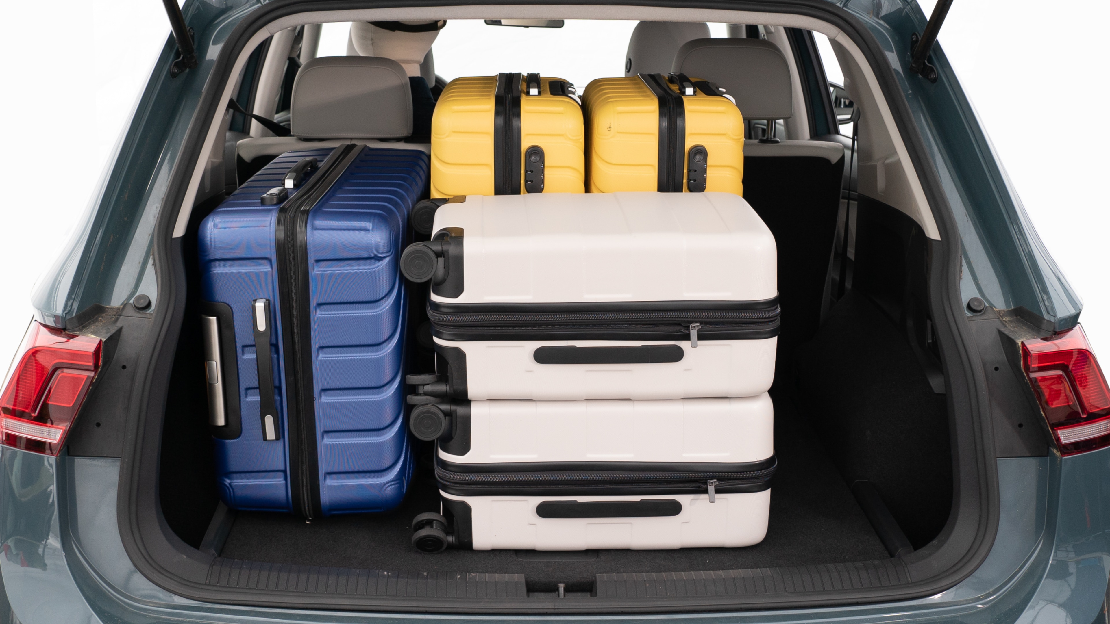 The trunk lid is open, showing a full view of the trunk space. Three large and two small suitcases are placed inside.