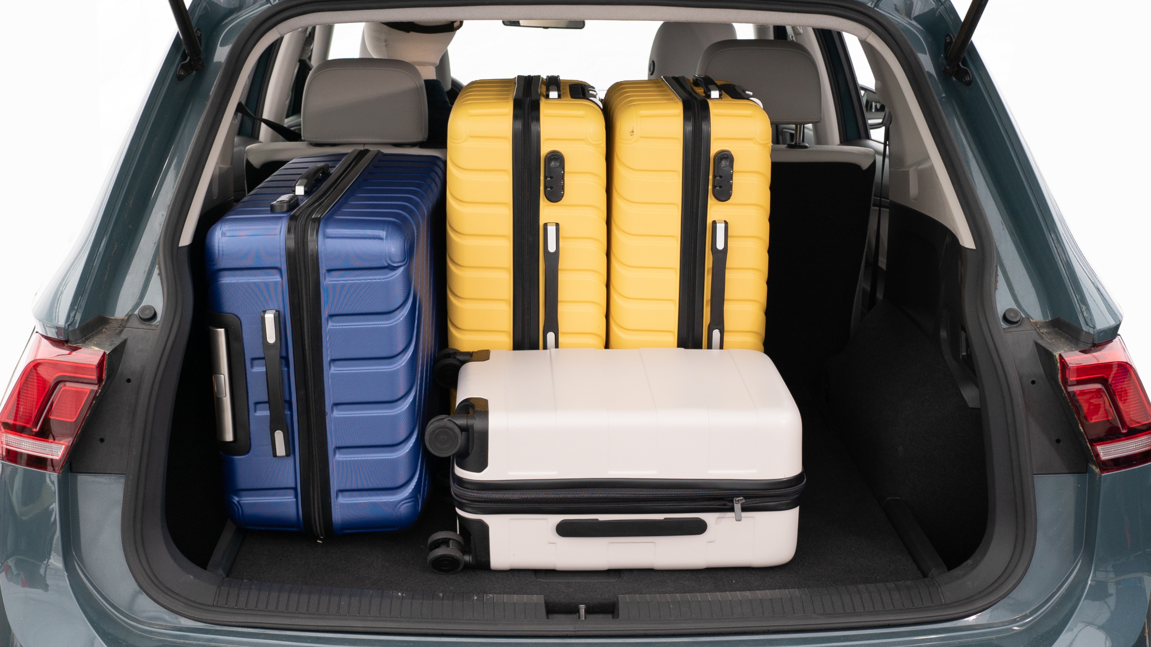 The trunk lid is open, showing a full view of the trunk space. Three large and two small suitcases are placed inside.