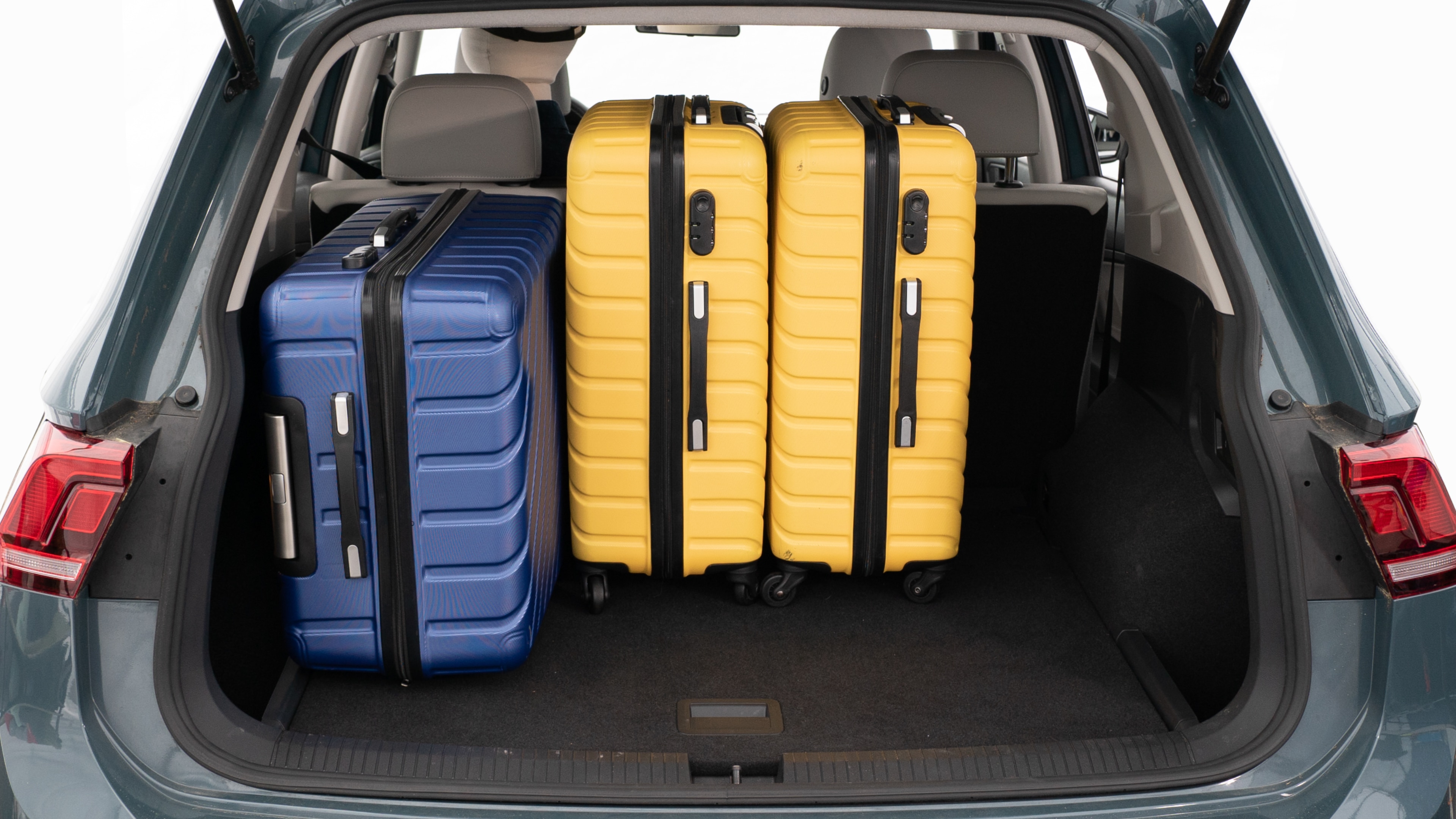 The trunk lid is open, showing a full view of the trunk space. Three large and two small suitcases are placed inside.