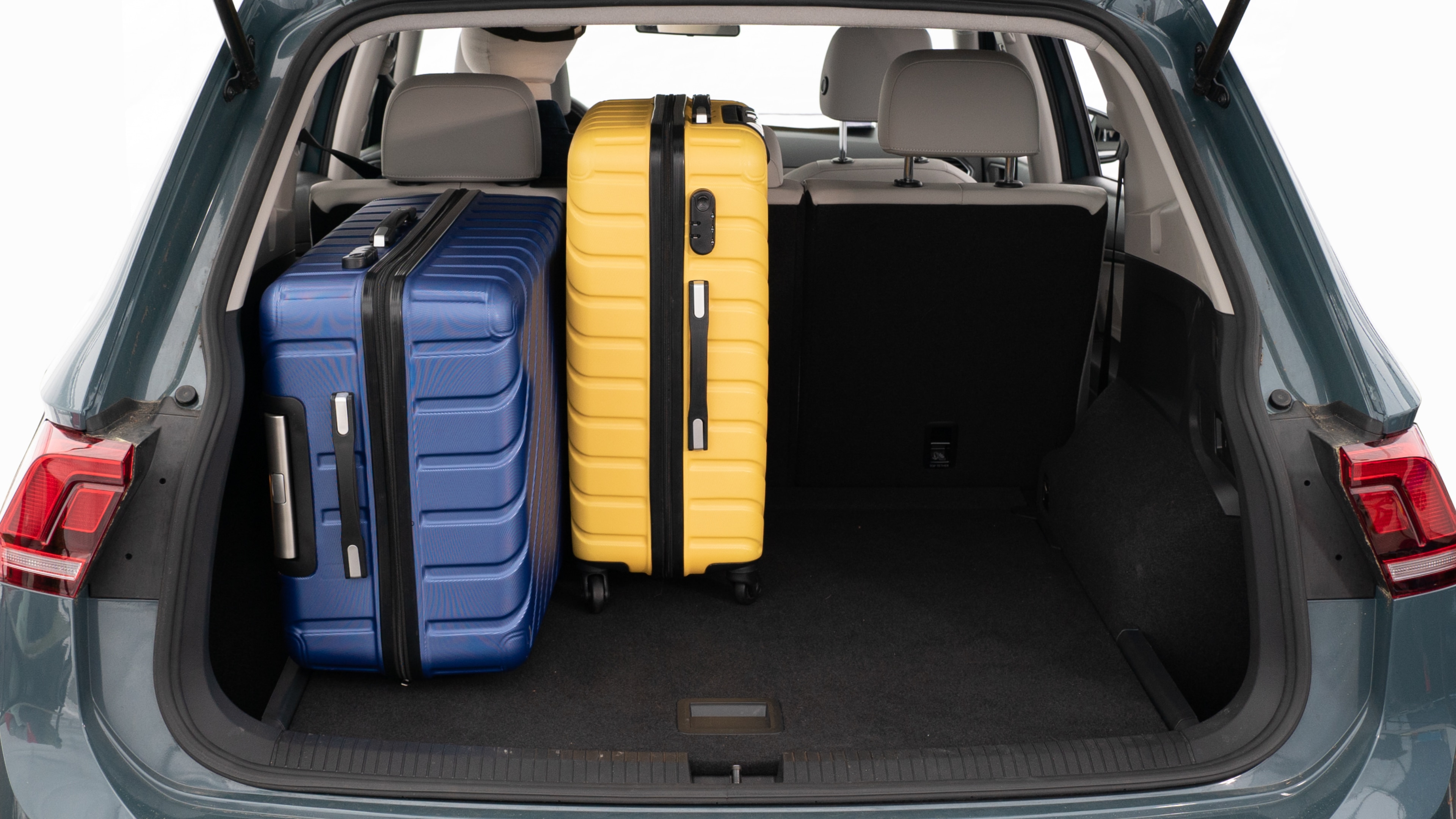 The trunk lid is open, showing a full view of the trunk space. Three large and two small suitcases are placed inside.