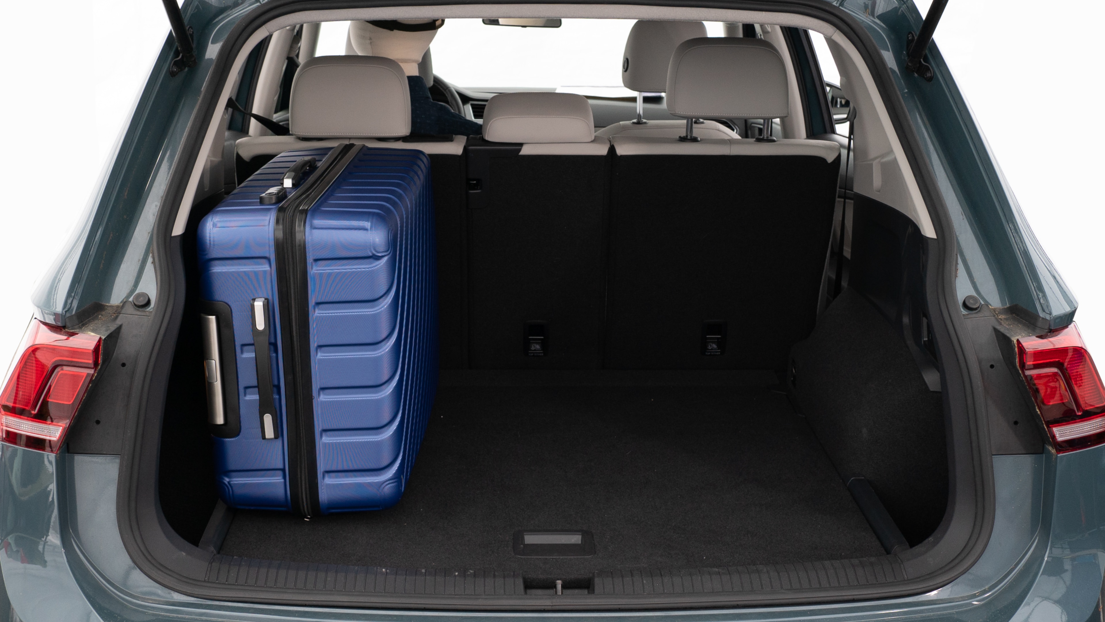 The trunk lid is open, showing a full view of the trunk space. Three large and two small suitcases are placed inside.