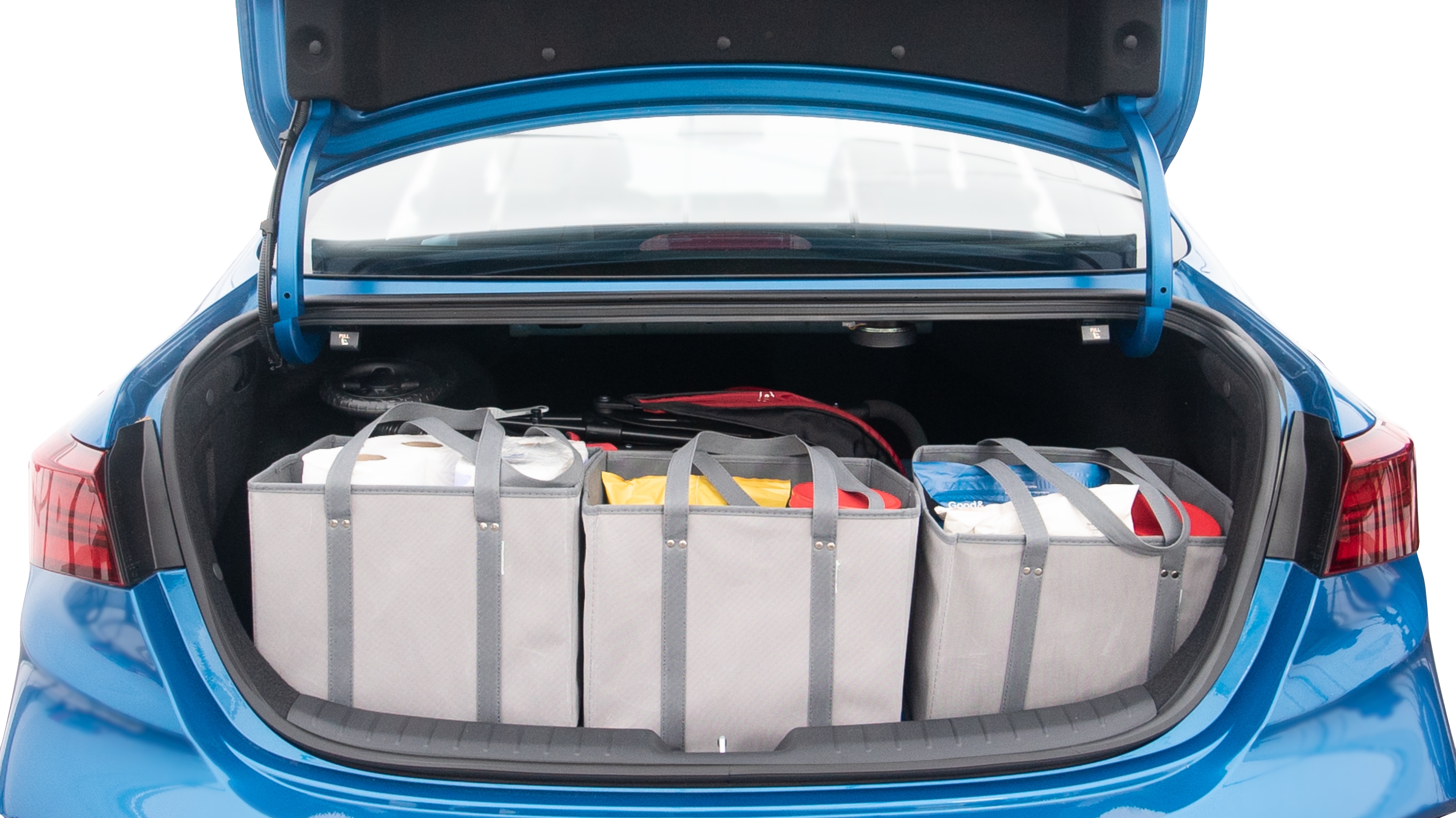 The trunk lid is open showing full view of the trunk. A baby stroller, three grocery carriers, two camping chairs in the carrying bag, and a set of golf clubs are placed inside.
