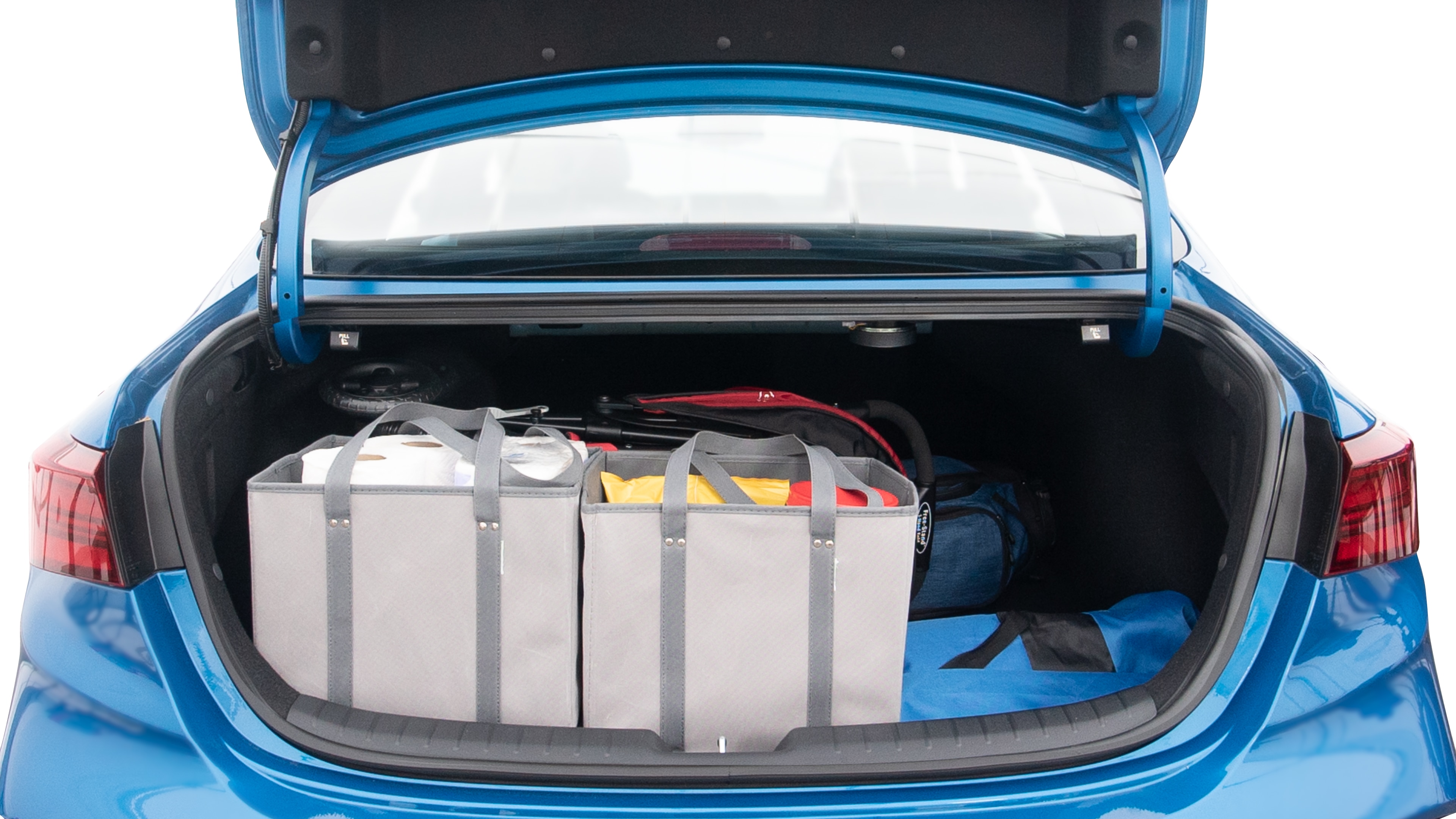 The trunk lid is open showing full view of the trunk. A baby stroller, three grocery carriers, two camping chairs in the carrying bag, and a set of golf clubs are placed inside.