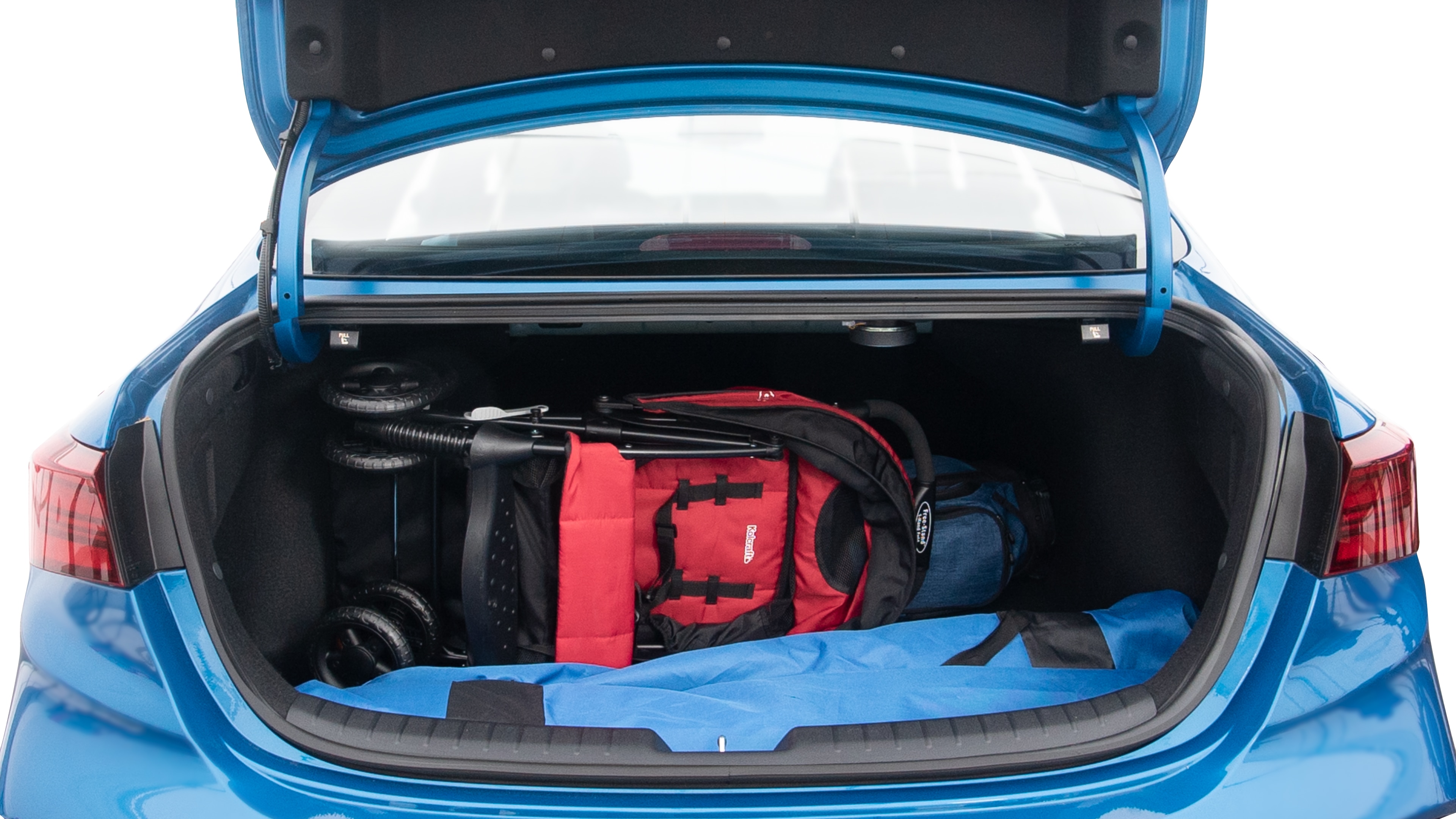 The trunk lid is open showing full view of the trunk. A baby stroller, three grocery carriers, two camping chairs in the carrying bag, and a set of golf clubs are placed inside.
