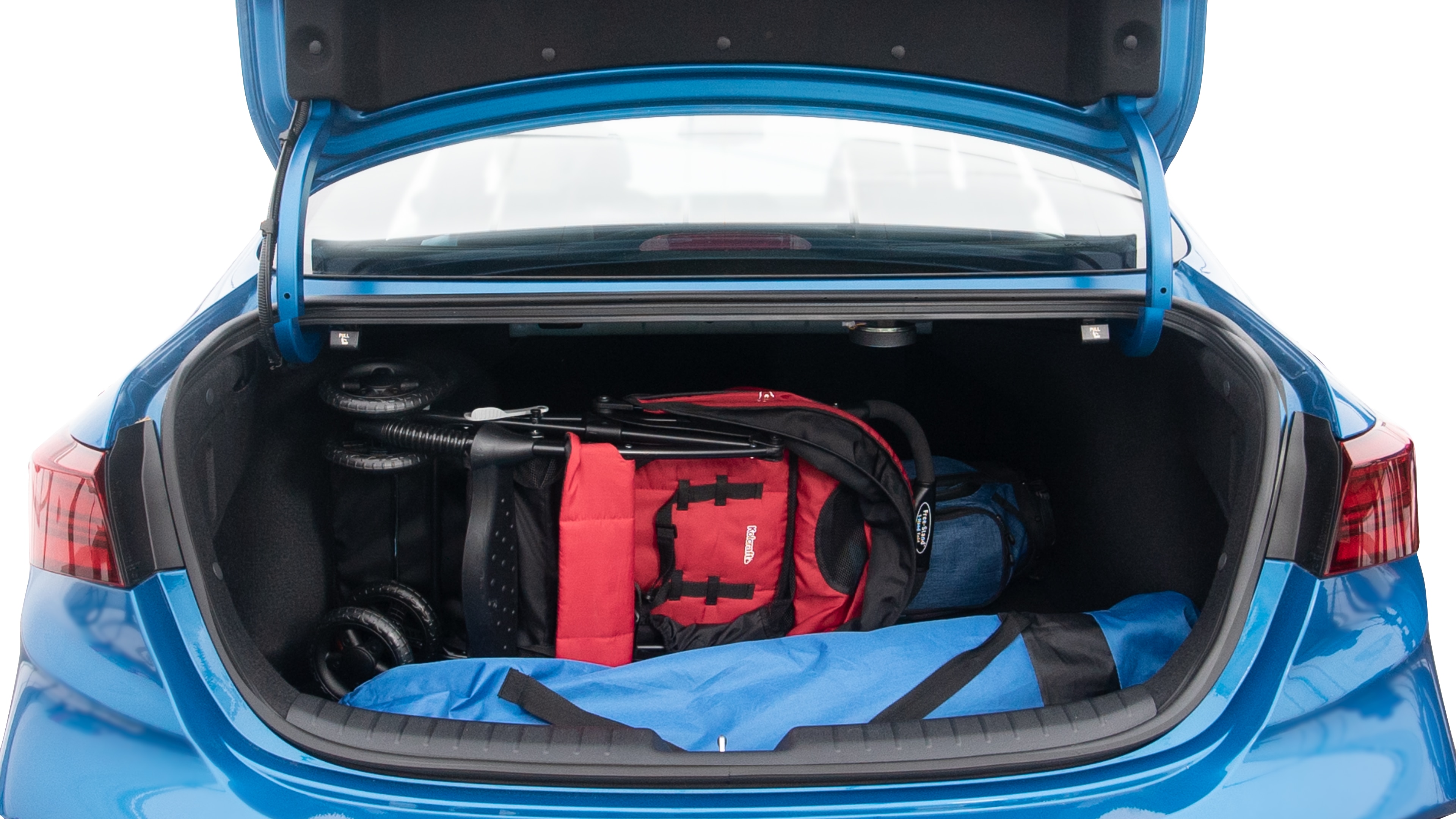 The trunk lid is open showing full view of the trunk. A baby stroller, three grocery carriers, two camping chairs in the carrying bag, and a set of golf clubs are placed inside.