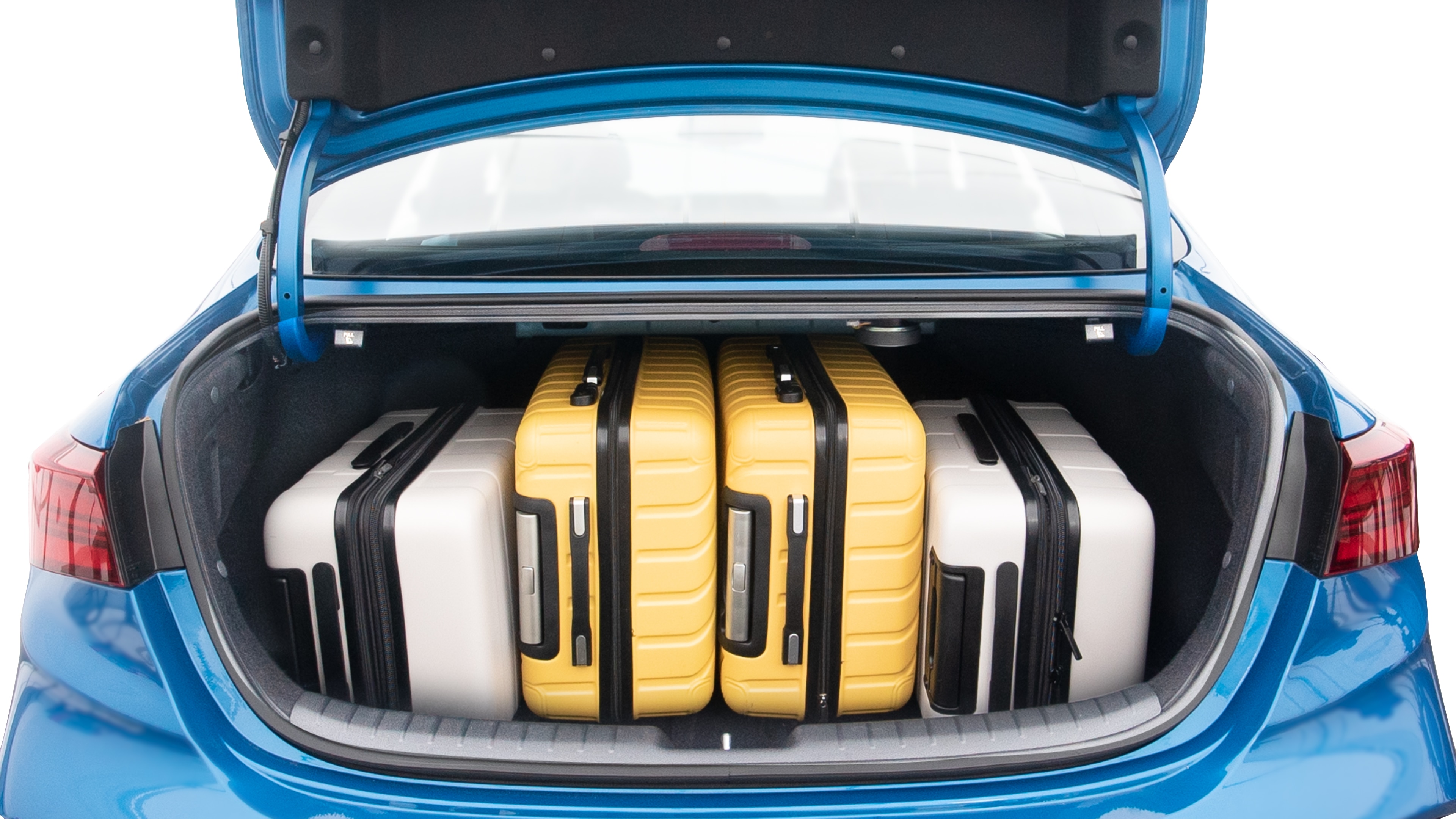 The trunk lid is open, showing full view of the trunk space. Two large and two small suitcases are placed inside.