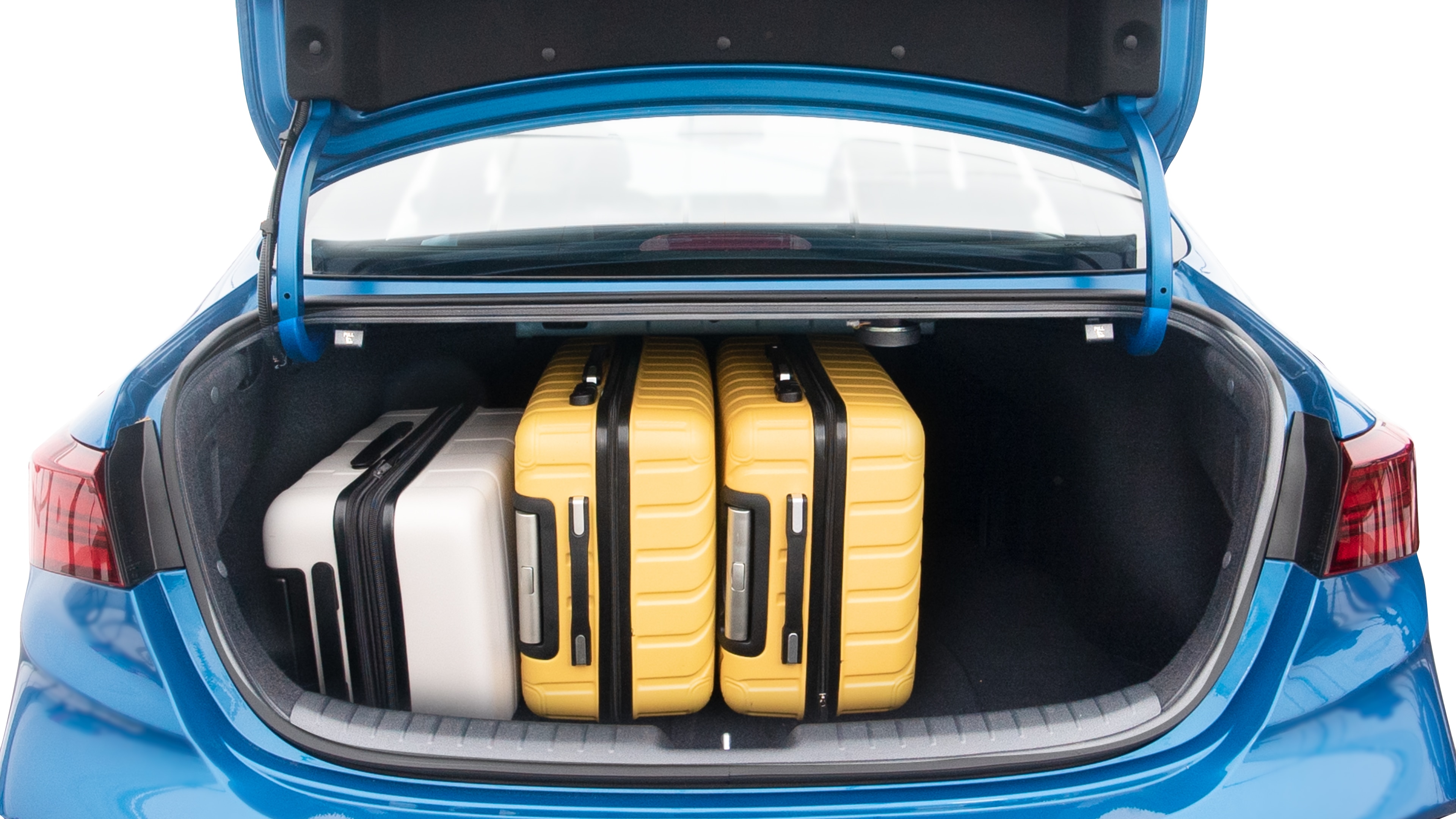 The trunk lid is open, showing full view of the trunk space. Two large and two small suitcases are placed inside.