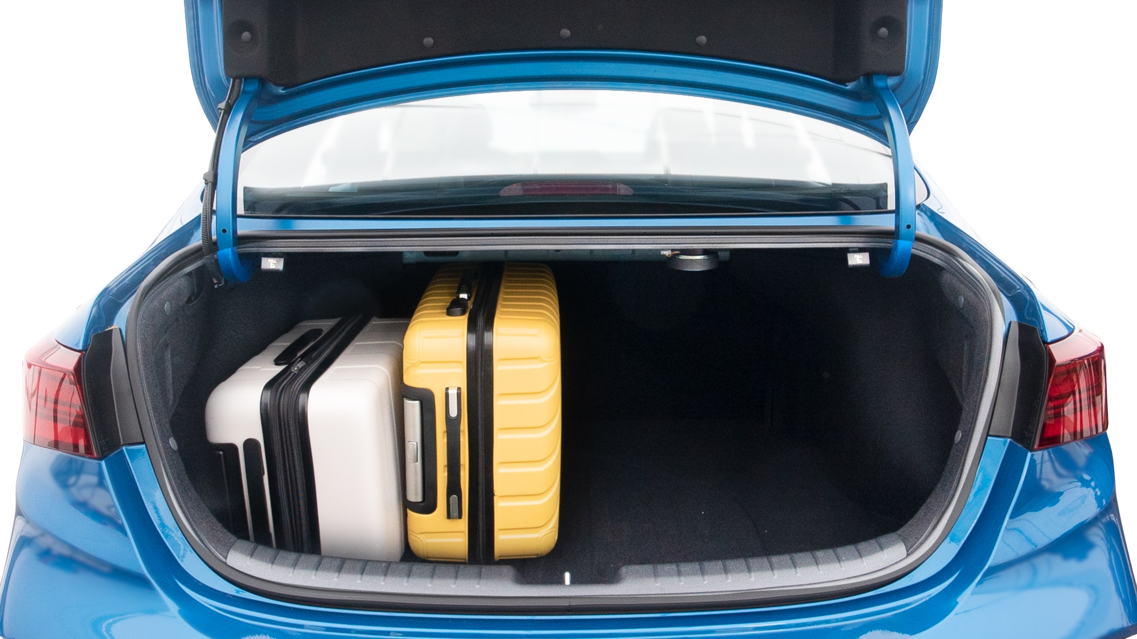 The trunk lid is open, showing full view of the trunk space. Two large and two small suitcases are placed inside.