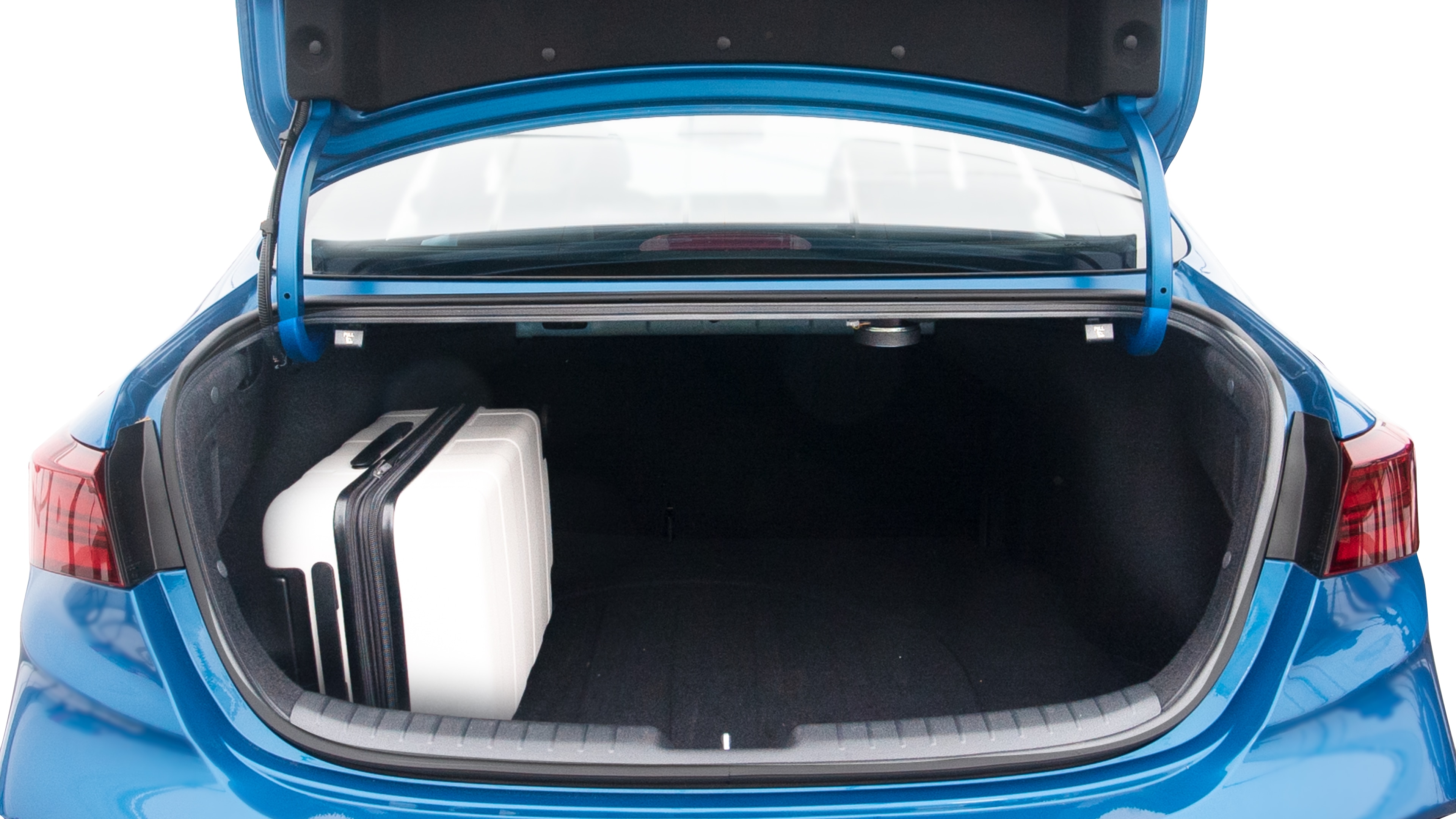 The trunk lid is open, showing full view of the trunk space. Two large and two small suitcases are placed inside.