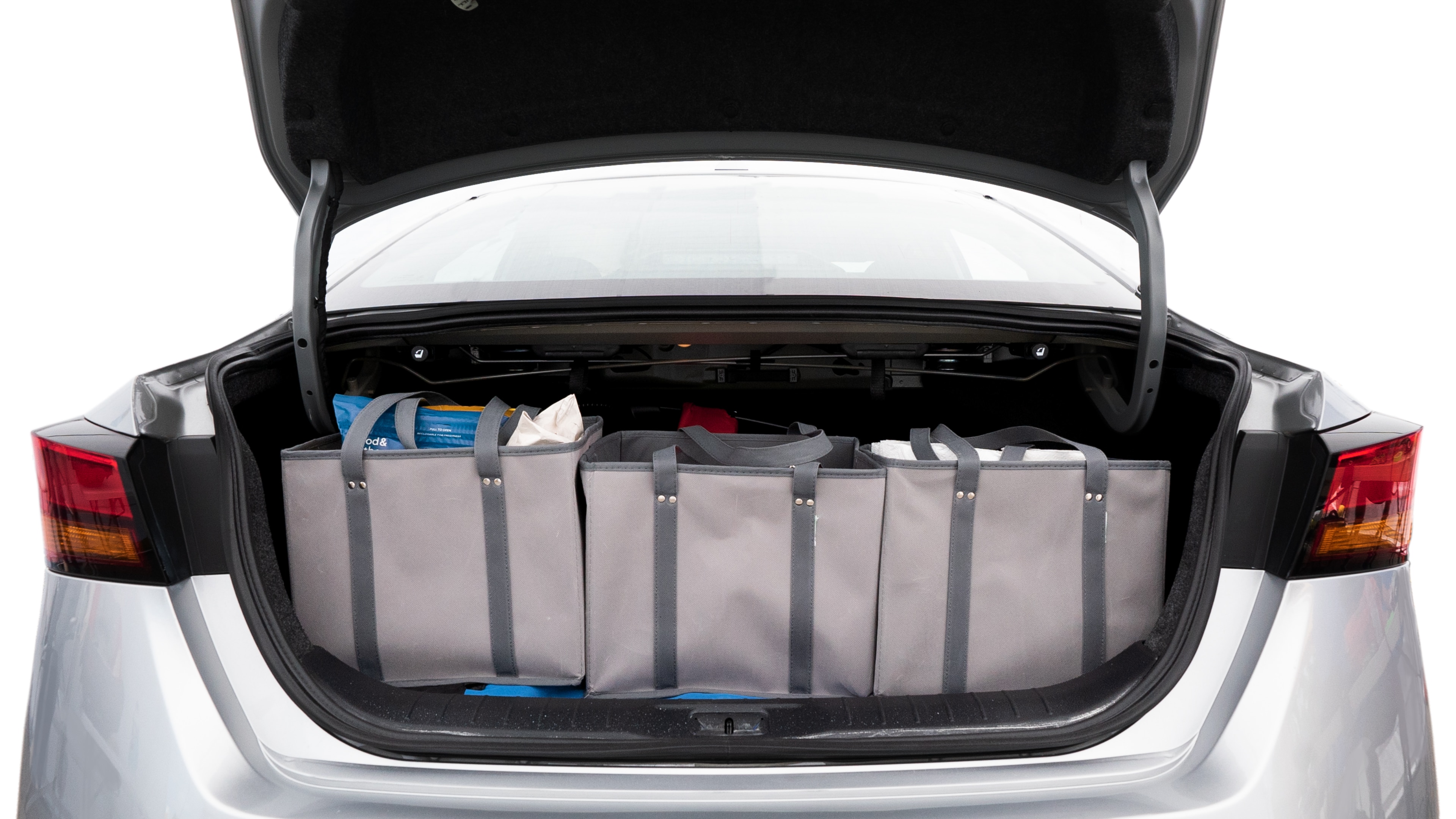 The trunk lid is open showing full view of the trunk. A baby stroller, three grocery carriers, two camping chairs in the carrying bag, and a set of golf clubs are placed inside.