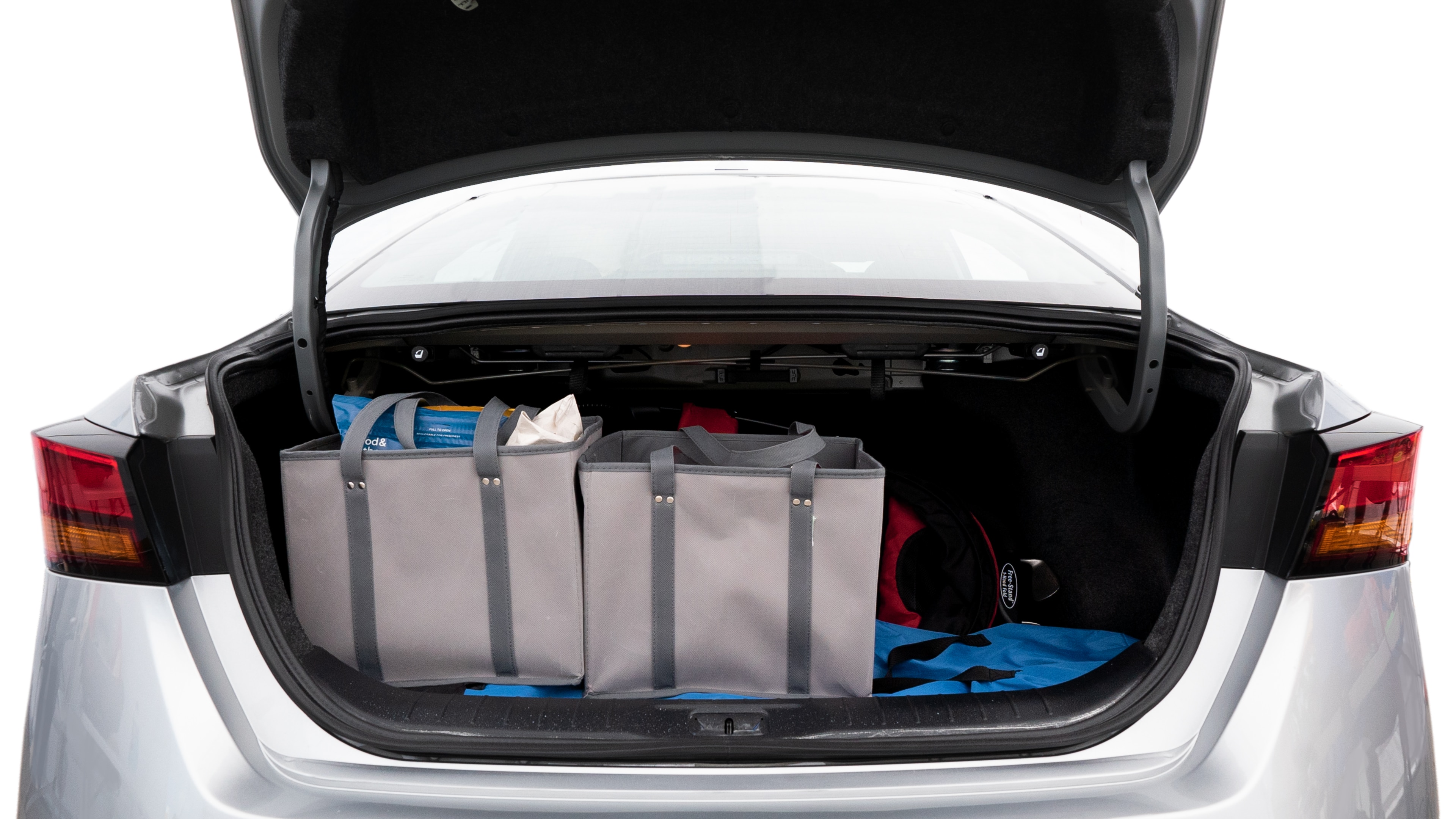 The trunk lid is open showing full view of the trunk. A baby stroller, three grocery carriers, two camping chairs in the carrying bag, and a set of golf clubs are placed inside.