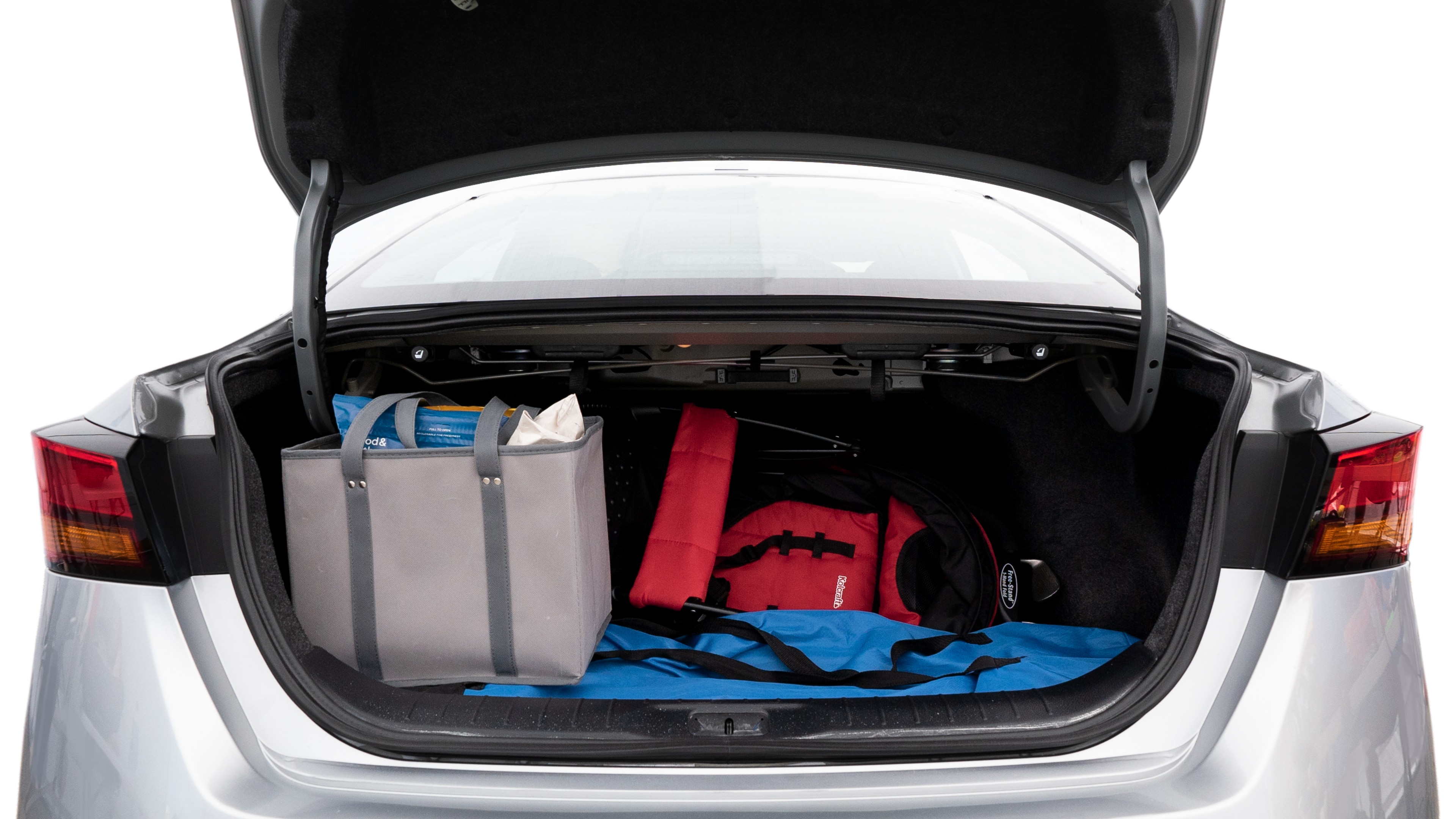 The trunk lid is open showing full view of the trunk. A baby stroller, three grocery carriers, two camping chairs in the carrying bag, and a set of golf clubs are placed inside.