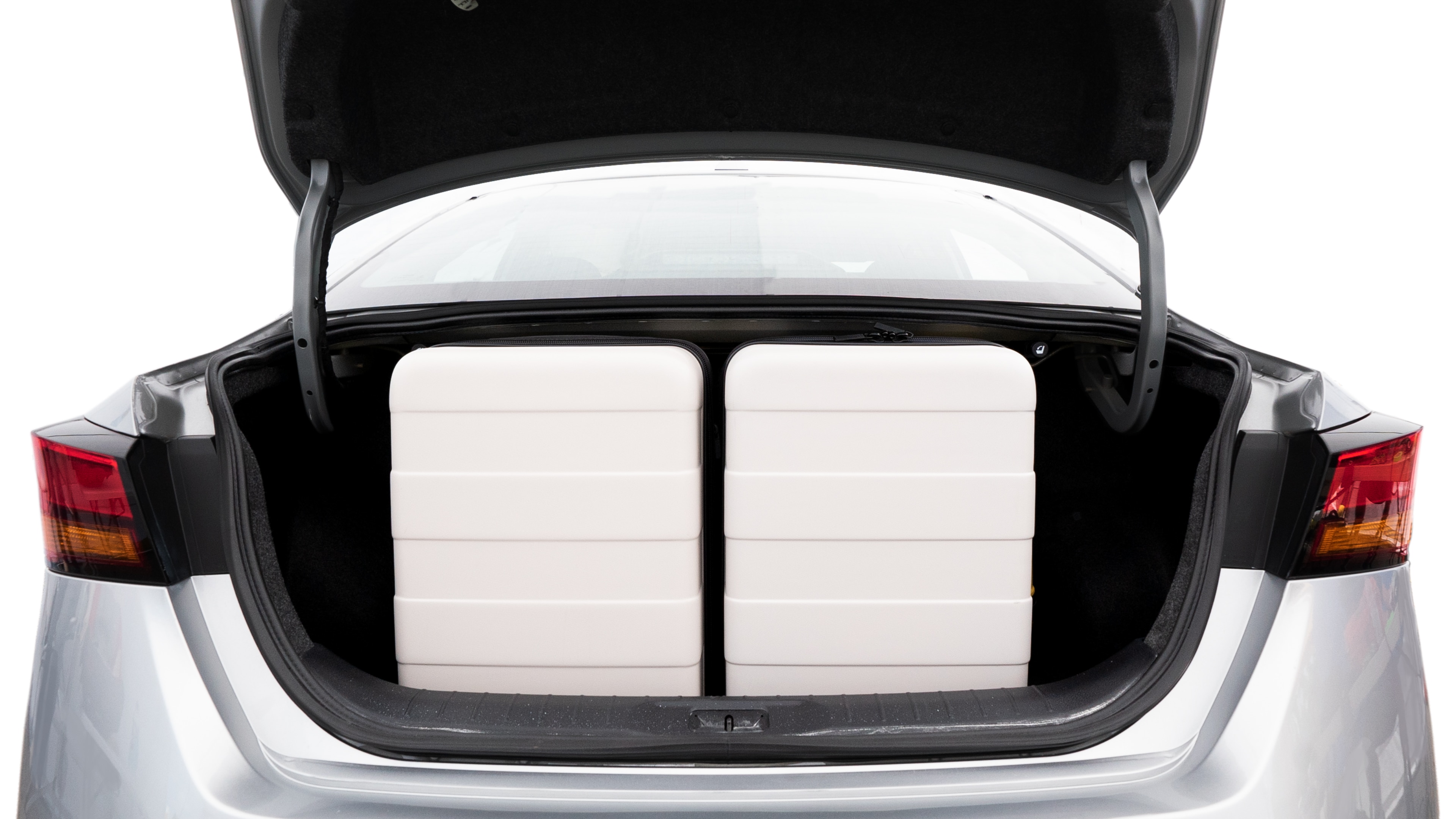 The trunk lid is open, showing full view of the trunk space. Two medium and two small suitcases are placed inside.