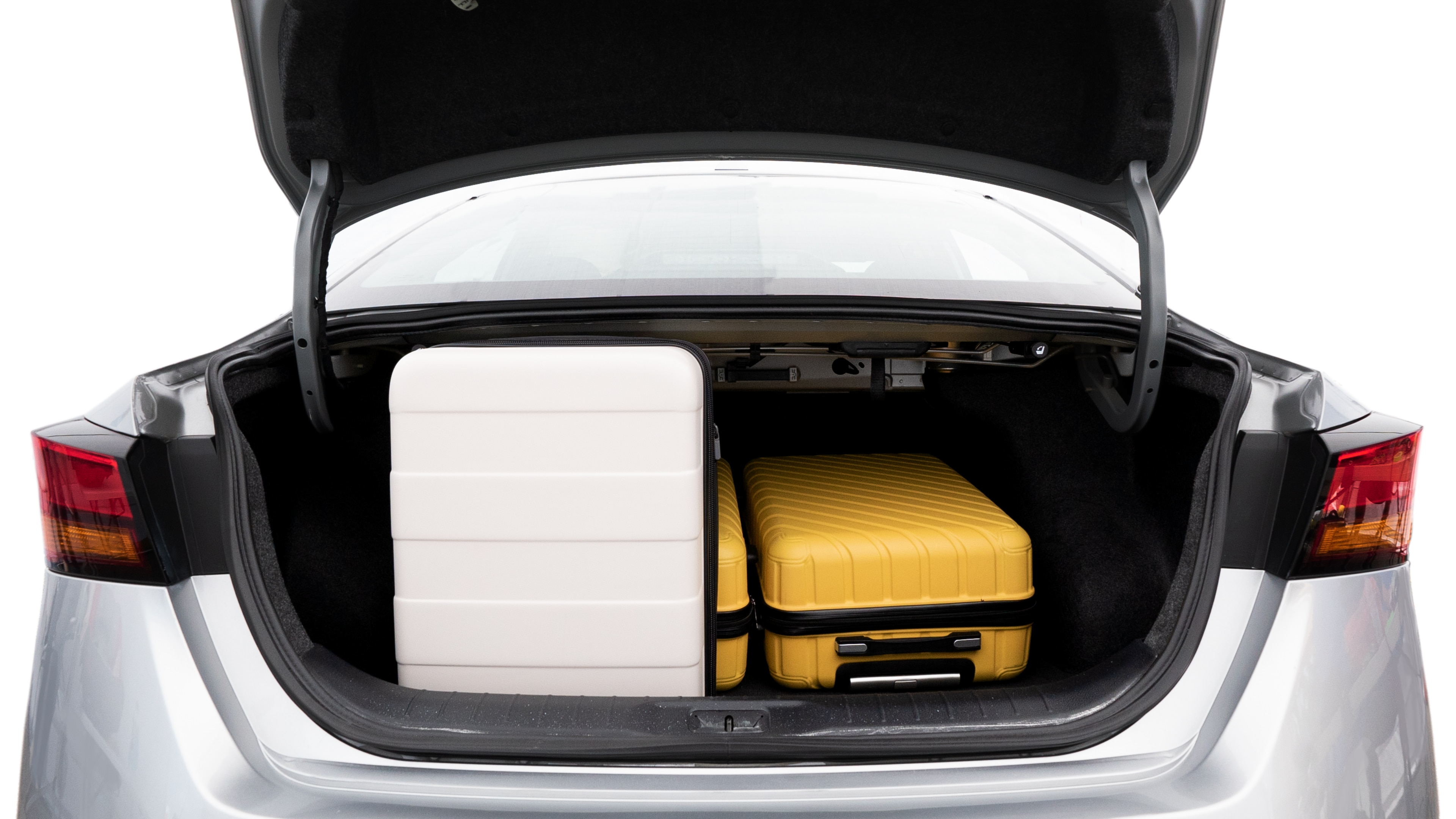 The trunk lid is open, showing full view of the trunk space. Two medium and two small suitcases are placed inside.