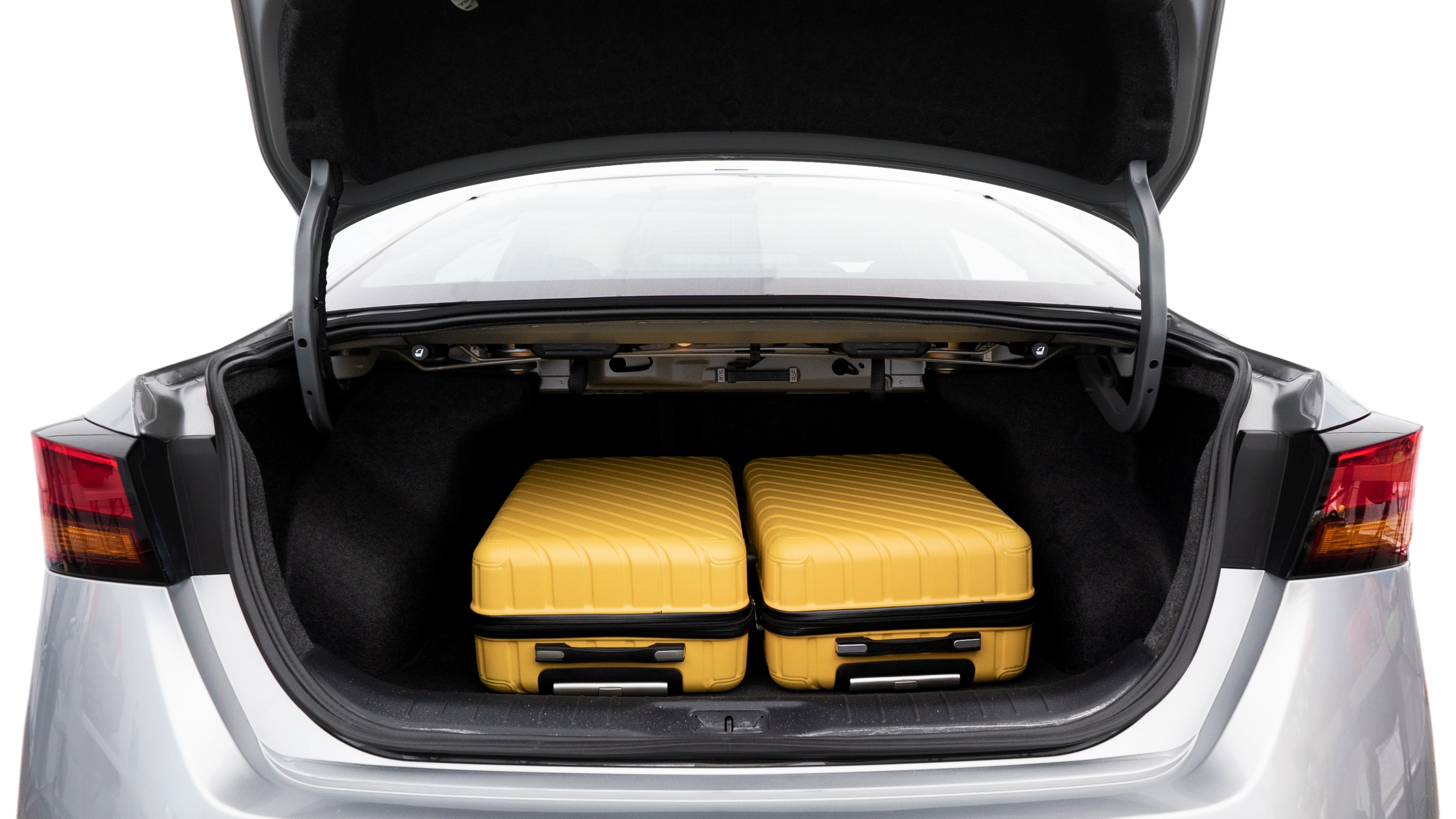 The trunk lid is open, showing full view of the trunk space. Two medium and two small suitcases are placed inside.