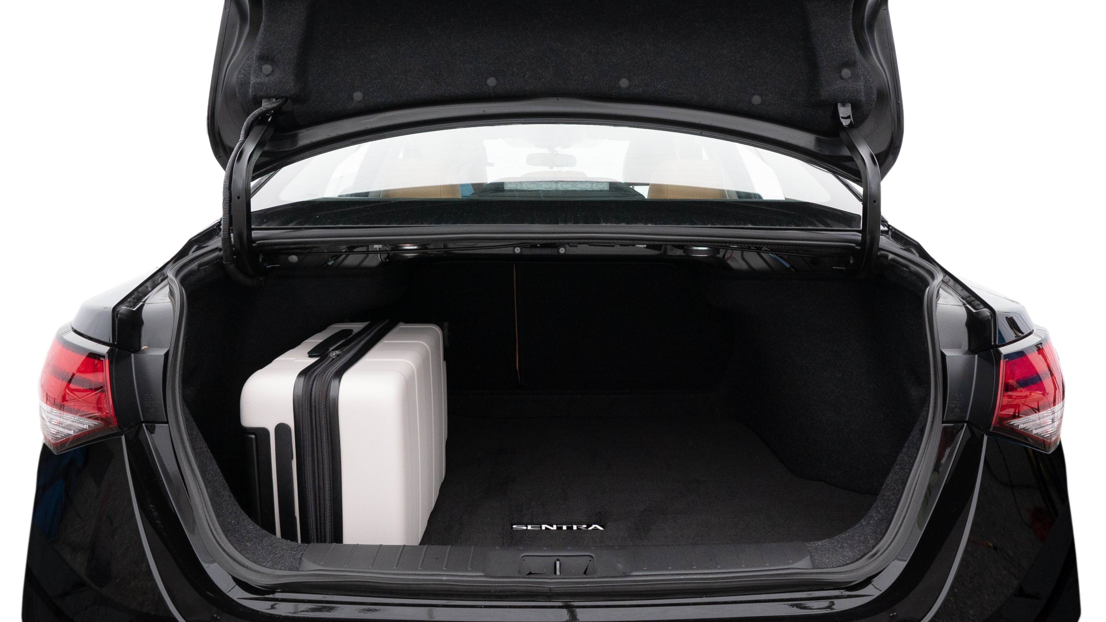 The trunk lid is open, showing full view of the trunk space. Two medium and two small suitcases are placed inside.