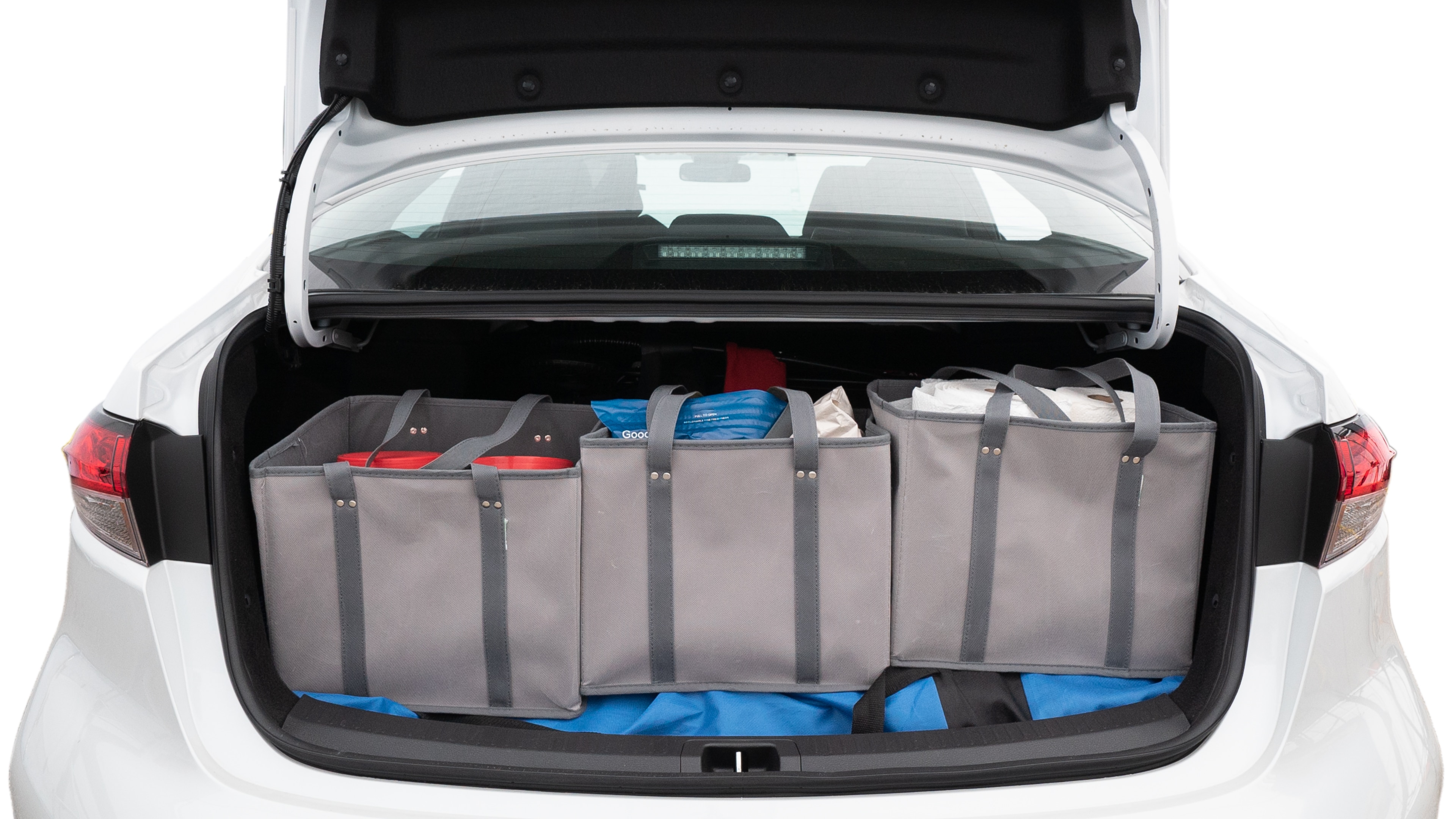 The trunk lid is open showing full view of the trunk. A baby stroller, three grocery carriers, two camping chairs in the carrying bag, and a set of golf clubs are placed inside.
