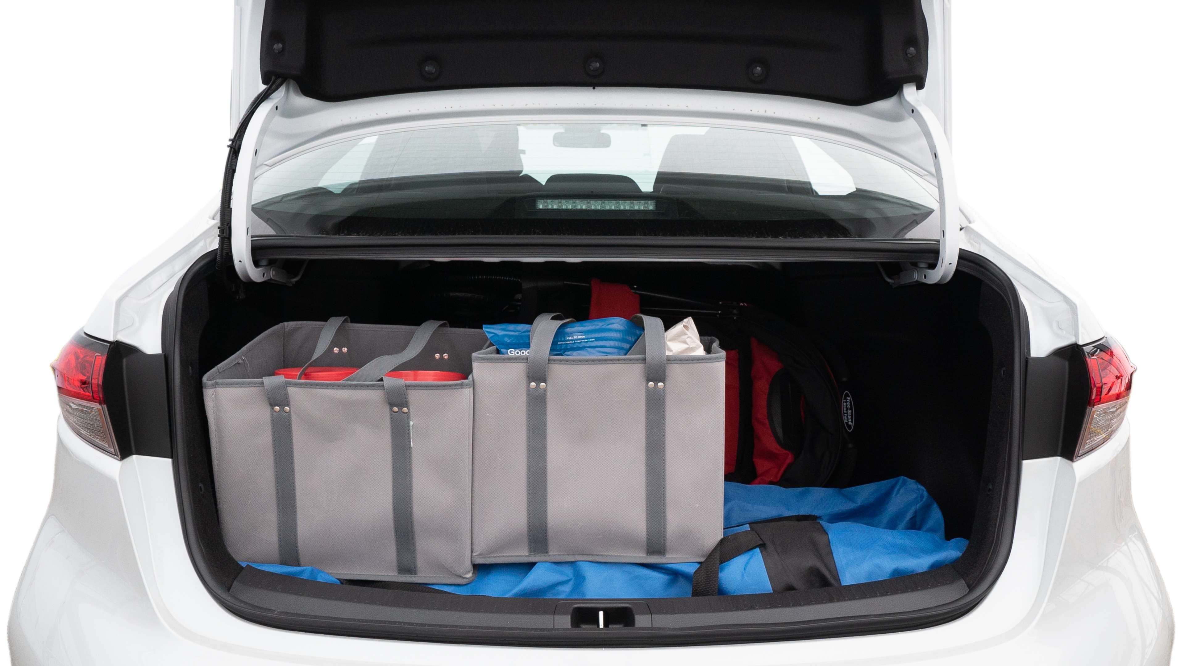 The trunk lid is open showing full view of the trunk. A baby stroller, three grocery carriers, two camping chairs in the carrying bag, and a set of golf clubs are placed inside.